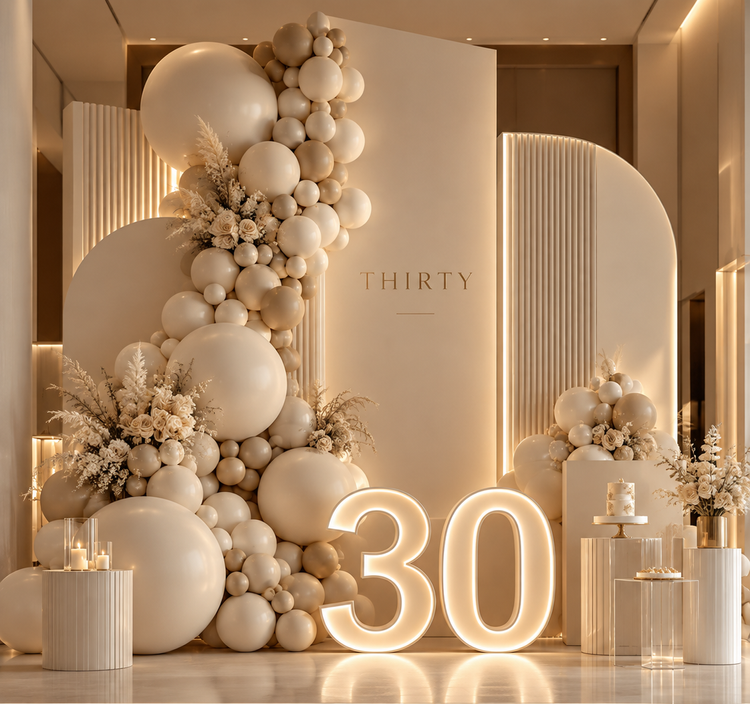 Neutral milestone birthday backdrop with balloon décor, floral accents and illuminated 30 numerals.