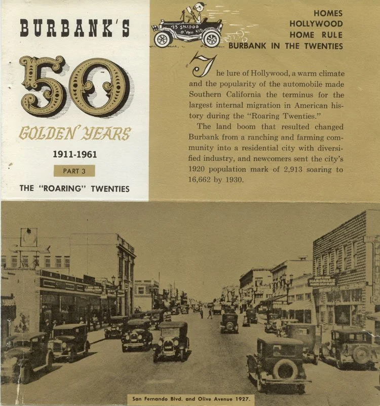 Vintage black and white photograph of San Fernando Blvd and Olive Avenue in 1927 showing cars parked on both sides of the street, with buildings and shops lining the street.