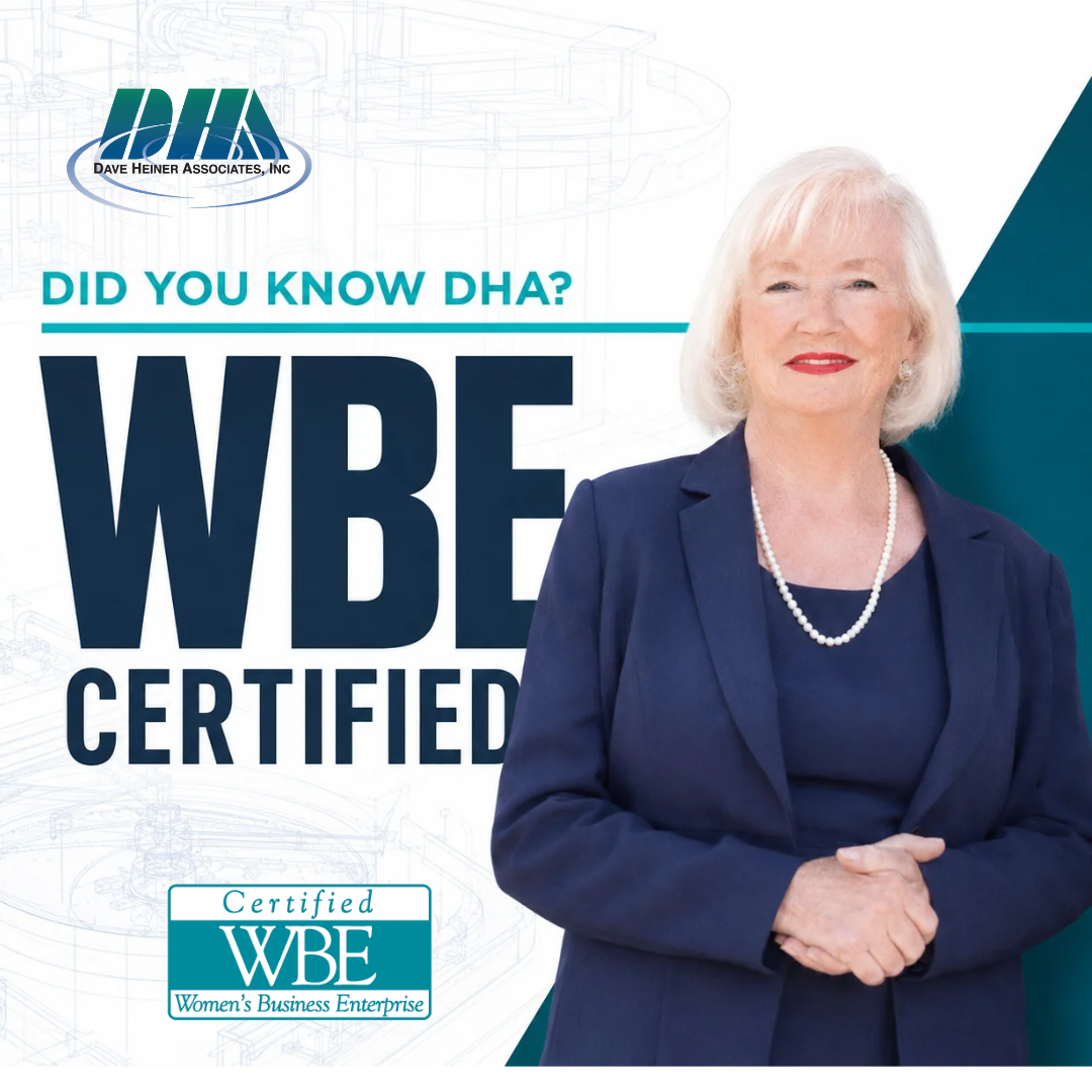 A smiling woman in a navy blazer and pearls standing in front of a graphic background that promotes WBE certification, with text about DHA and WBE certification from Women's Business Enterprise.