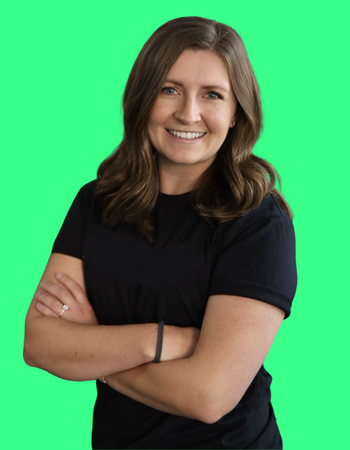 Young woman with shoulder-length brown hair, smiling, wearing a black t-shirt, standing with arms crossed against a green screen background.