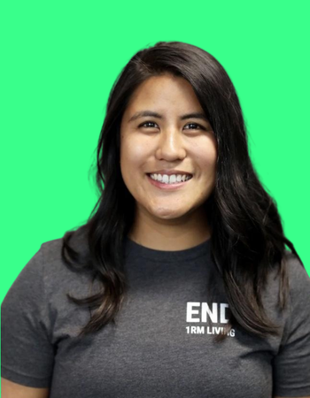 Young woman with long dark hair smiling, wearing a dark gray t-shirt against a green background.