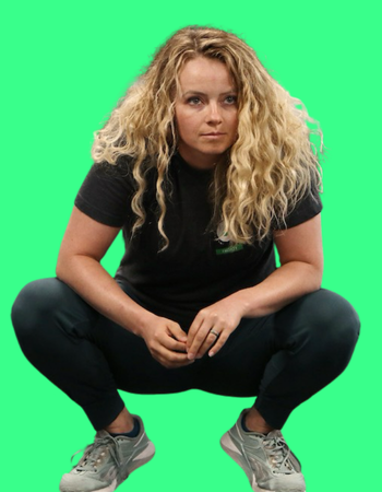 A woman with curly blonde hair squatting against a green screen background, wearing a black t-shirt, dark pants, and gray sneakers.