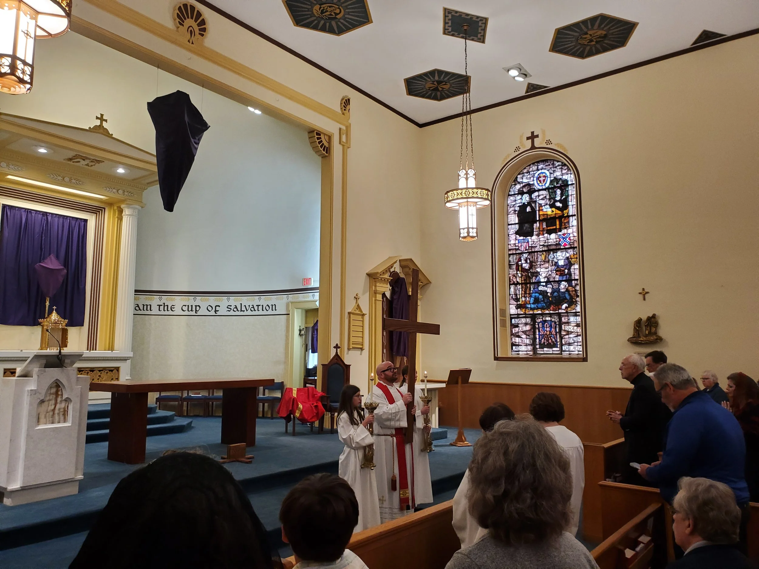 During the liturgy, parishioners encounter and venerate the cross---the symbol of Christ's victory over sin and death. Father awaits as parishioners get ready to come forward.