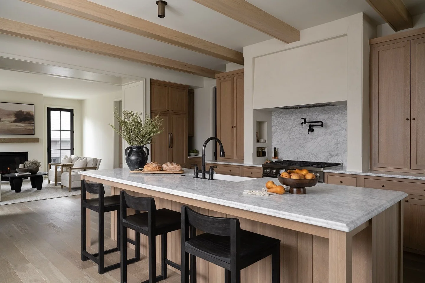 This kitchen was designed to balance beauty and function, featuring bar seating across the island that looks out to the windows, creating an inviting place to gather, linger, and enjoy the natural light. Thoughtful material selections, warm finishes,