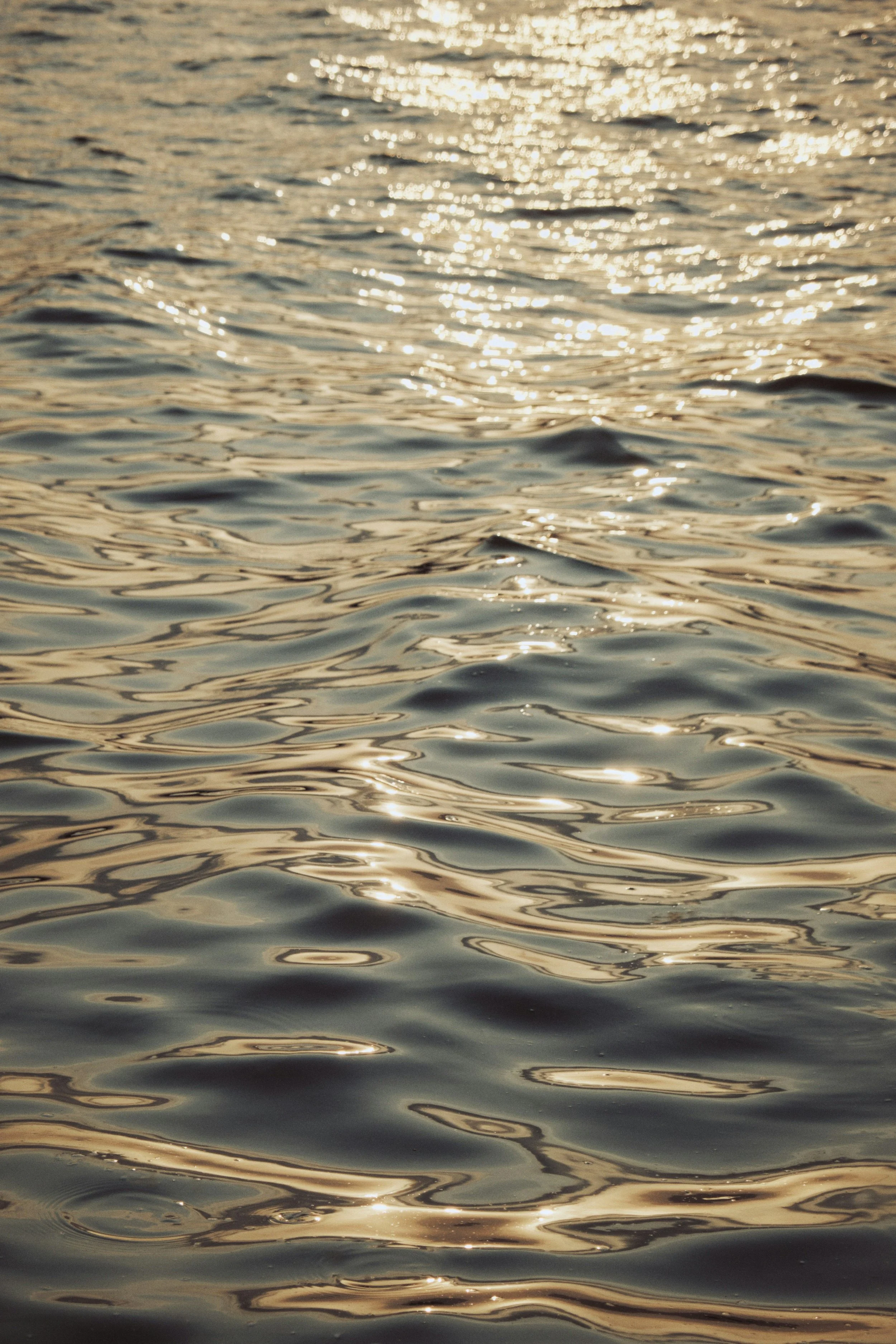 Sunlight reflecting on rippling water surface at sunset or sunrise.