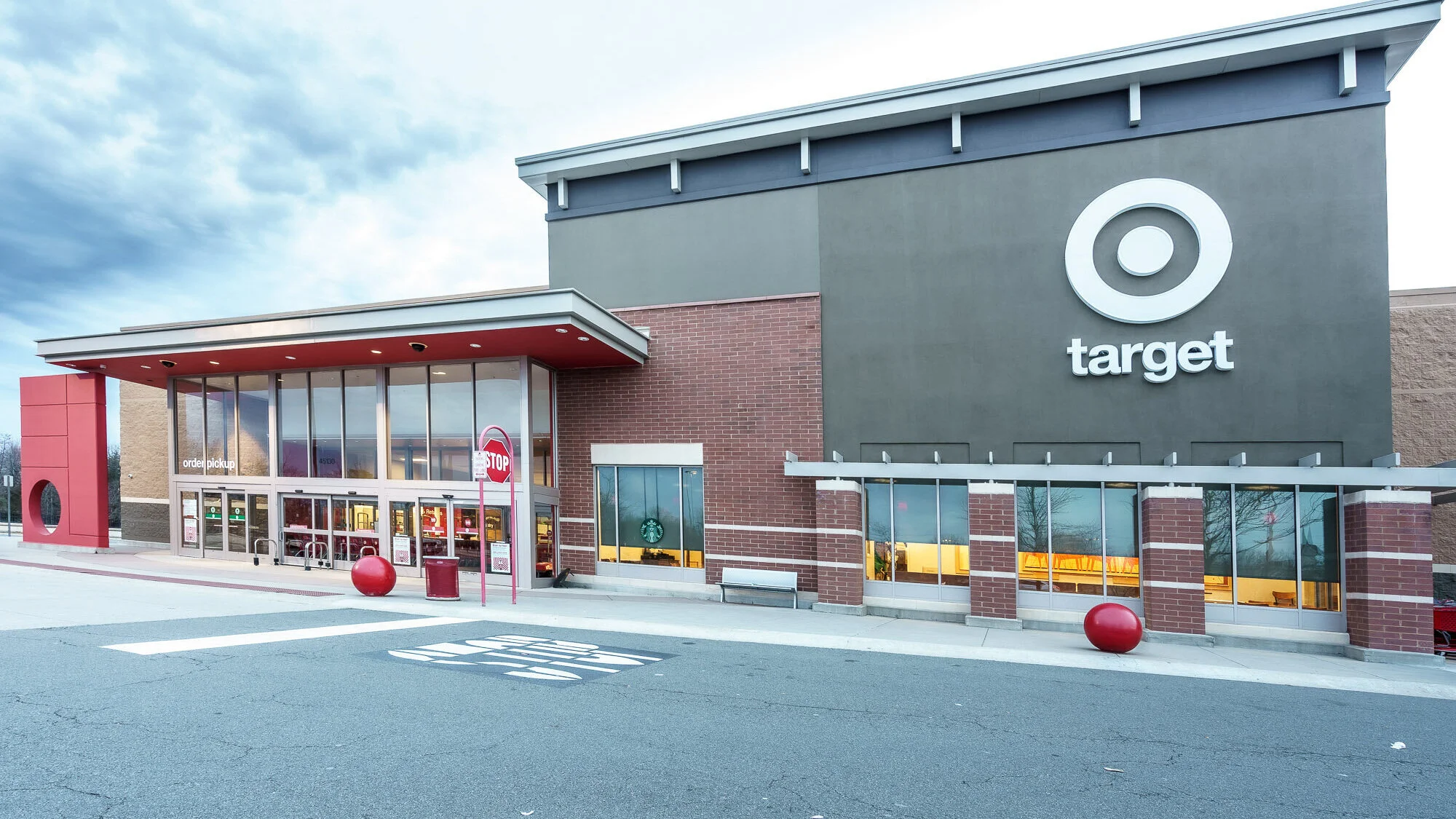 Exterior view of a Target store with large Target logo on the building, glass entrance doors, a stop sign, and red ball decor outside.