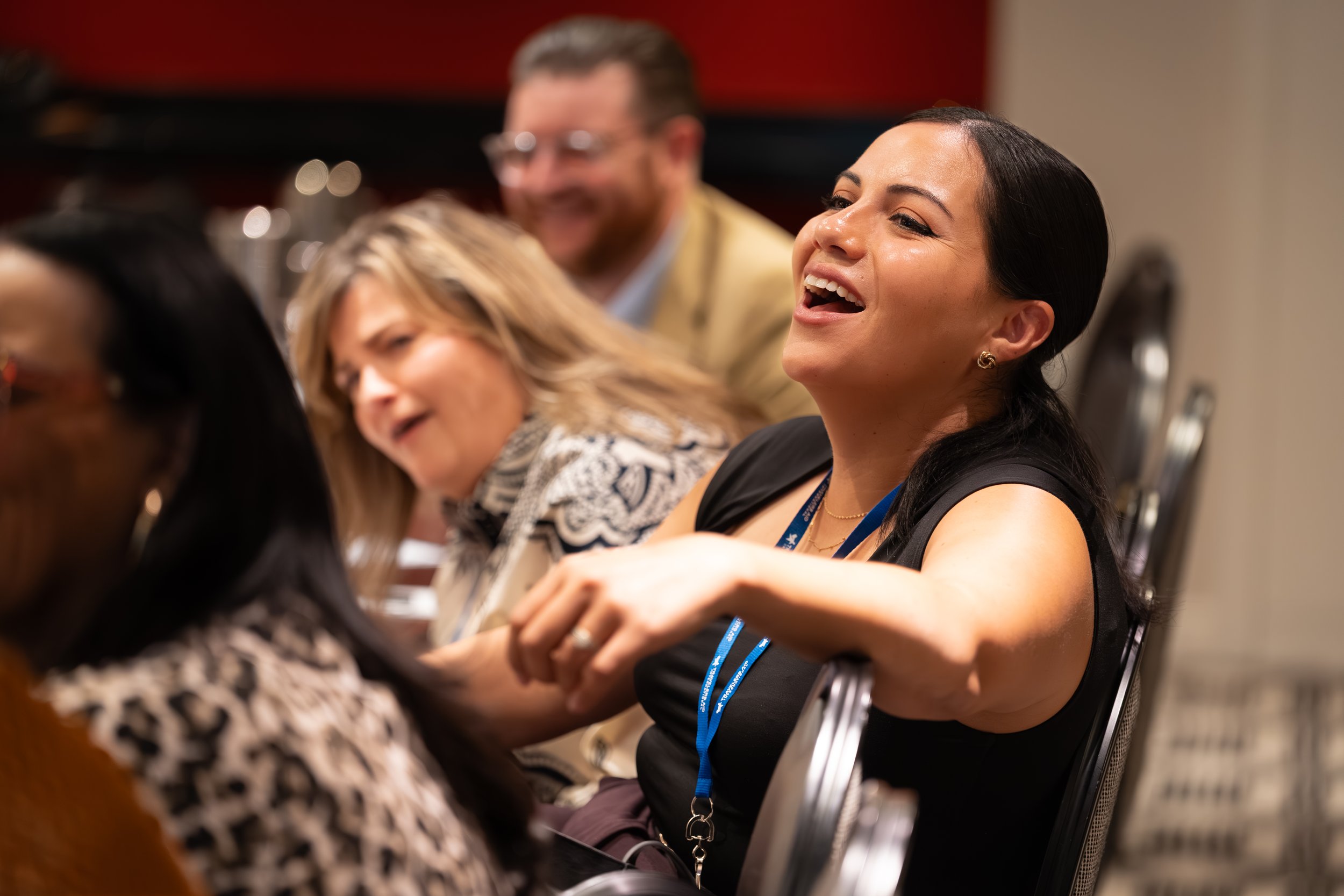 People seated at a conference or seminar, engaging and smiling