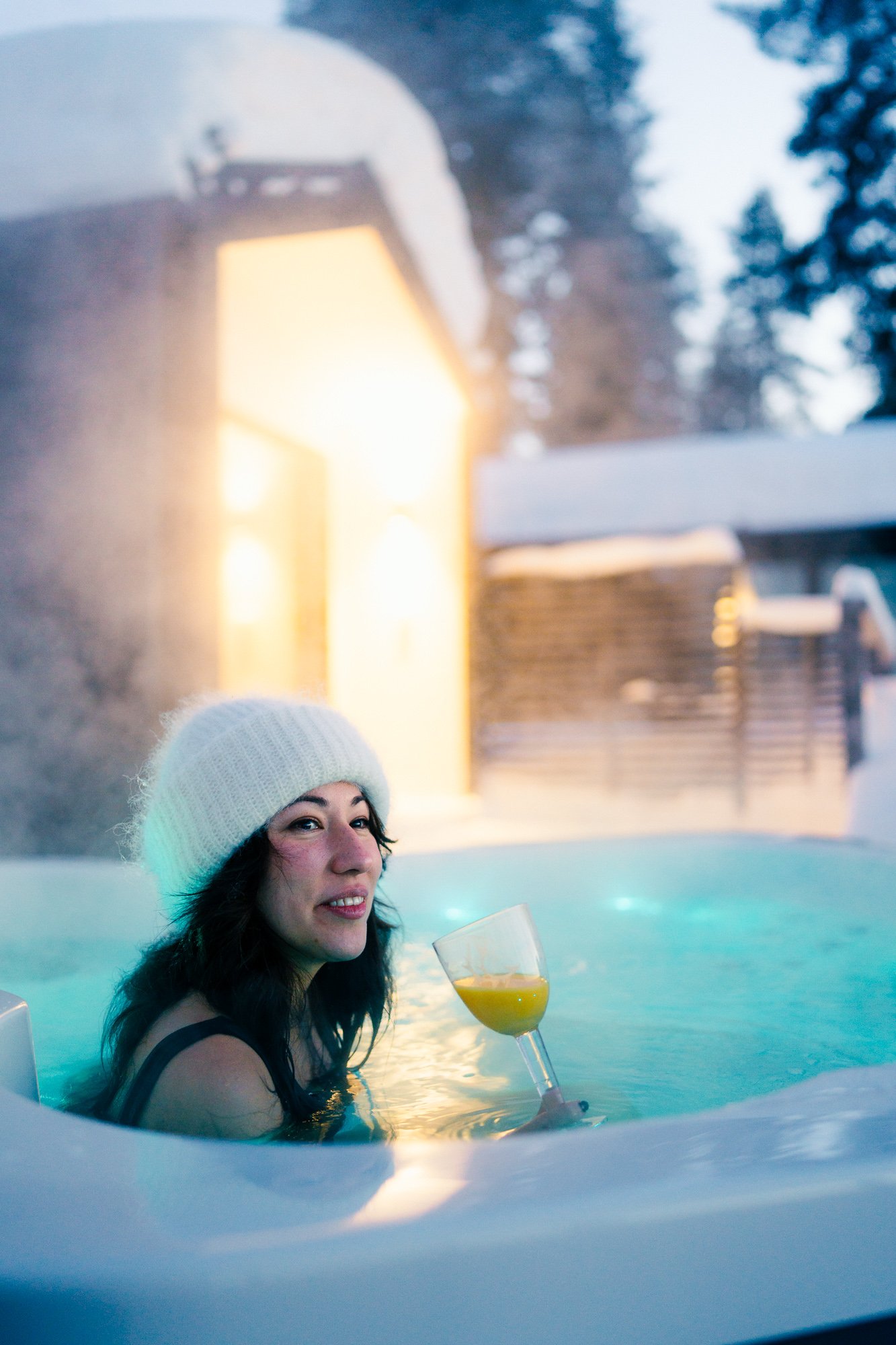 Dark haired woman with a white beanie sitting in a hot tub in Finnish Lapland and having a drink©Sami Laitinen.jpg