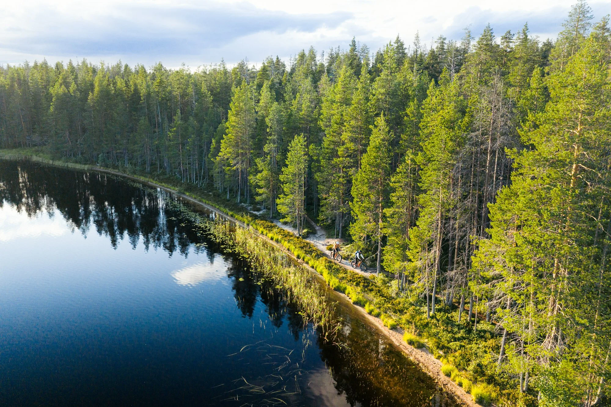 Suomussalmi-finland-kainuu-summer-kesä-biking adventure-bicycle-polkupyörä-fatbike-woman and man smiling-cycling close to the water-drone image-ilmakuva-hossan kansallispuisto-national park.jpg