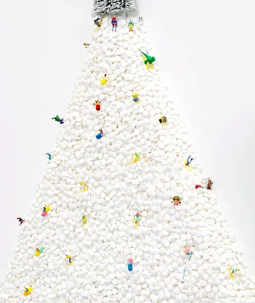 A Christmas tree made of marshmallows, decorated with small miniature figures and topped with artificial snow.