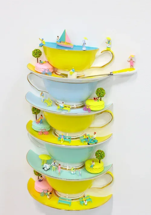 Stacked teacups with miniature summer scene decorations including people, trees, and boats