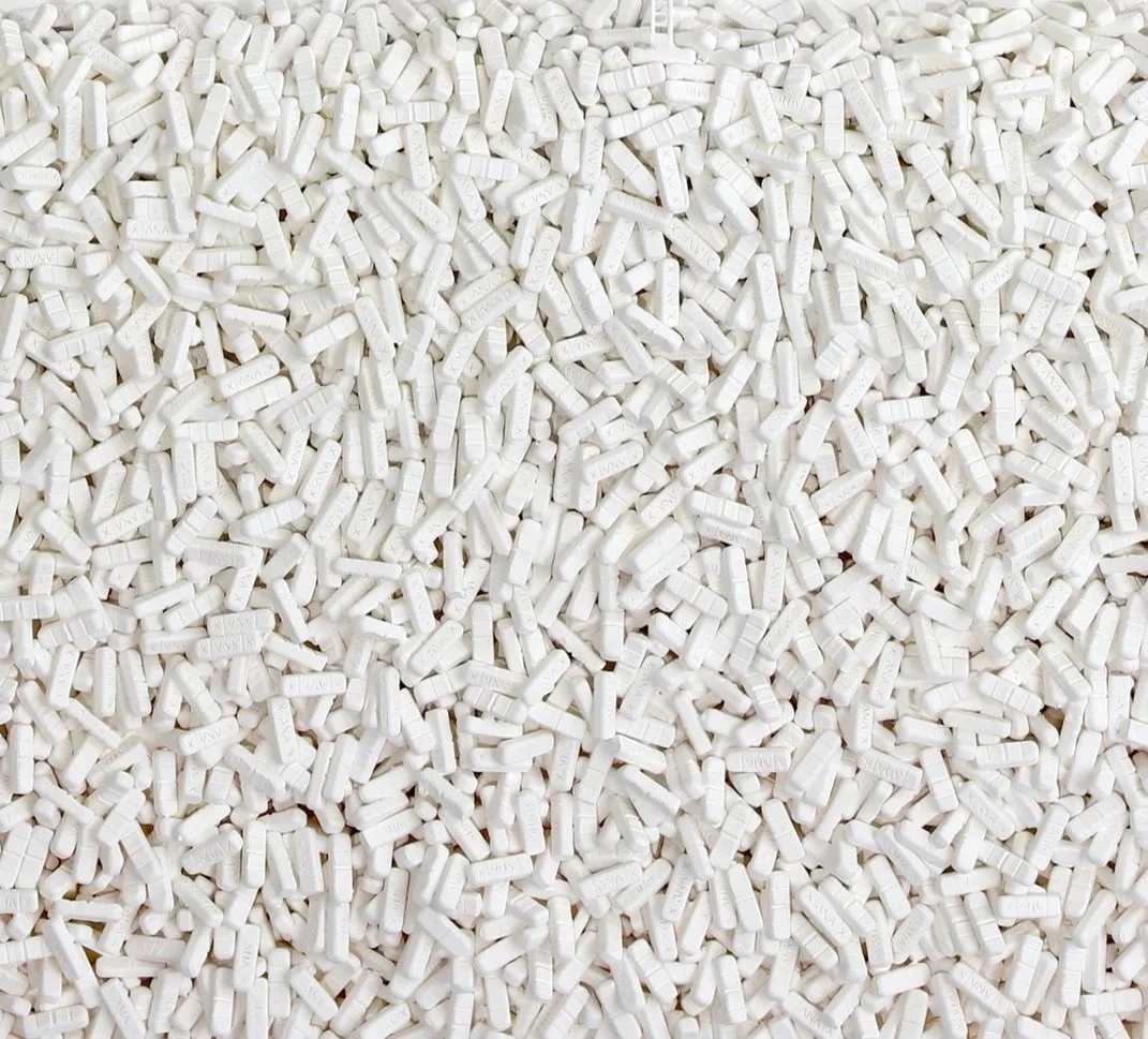 A large collection of white aspirin tablets piled together.