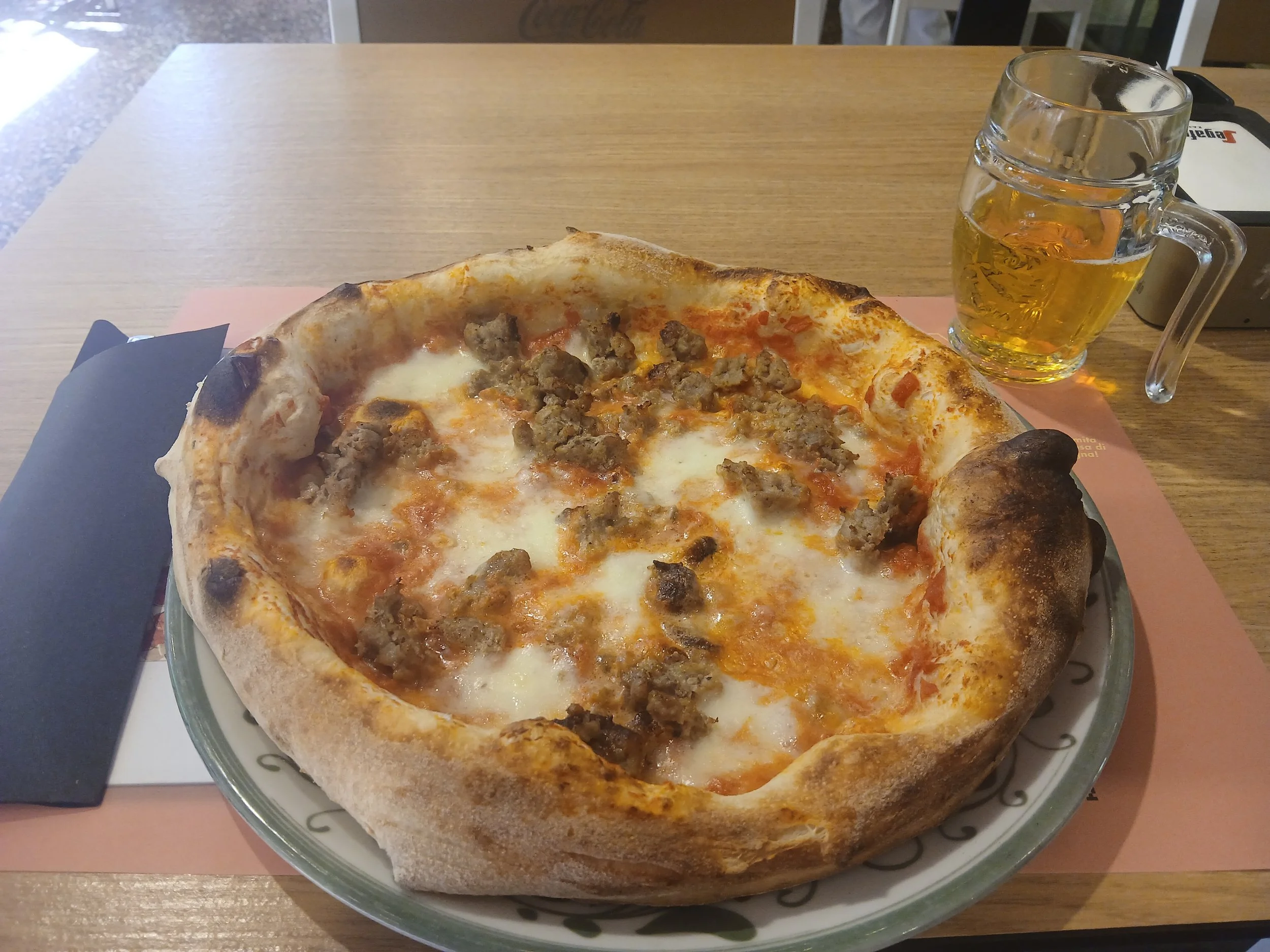 Pizza mit Salsiccia auf einem Holztisch