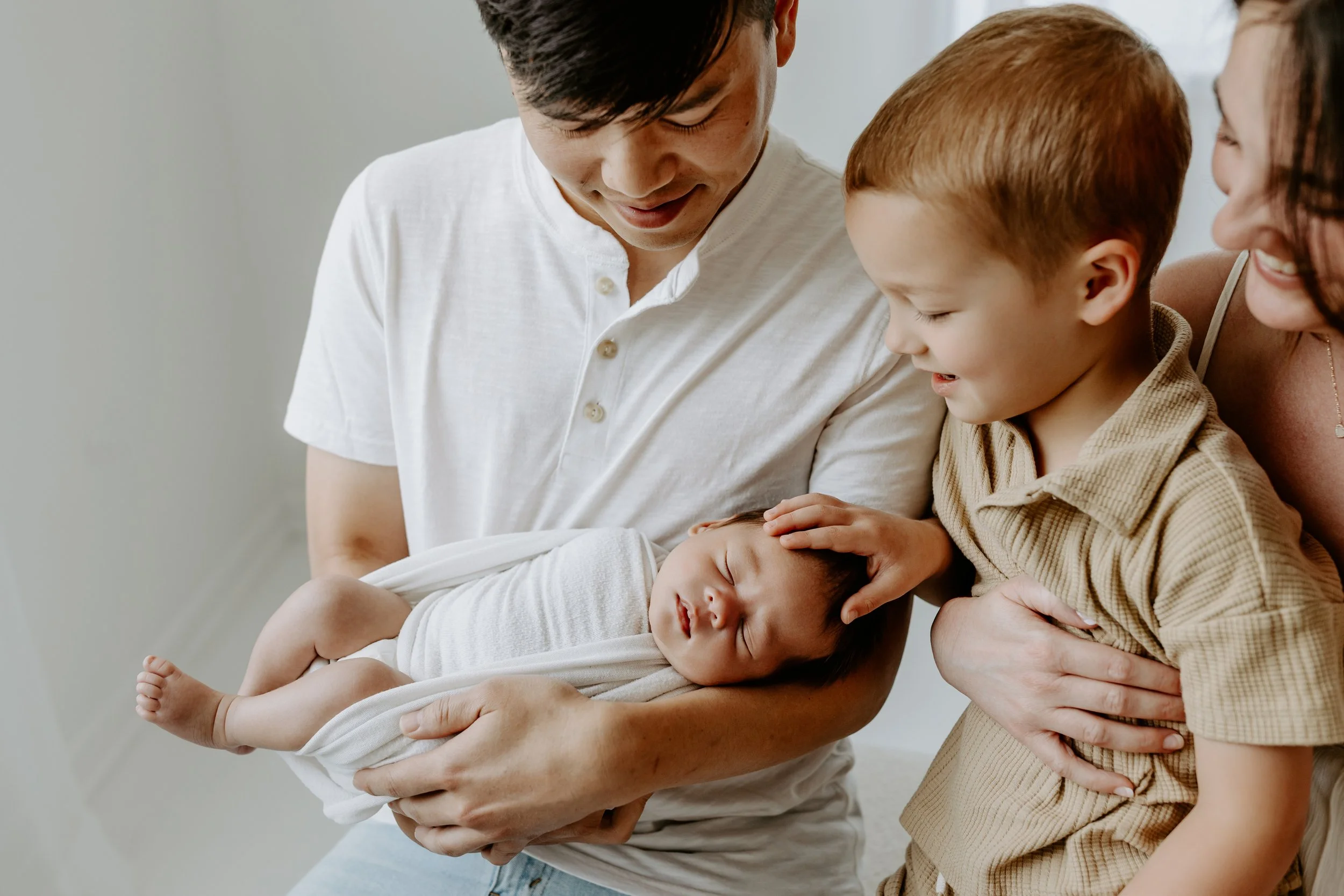 Family with a newborn baby in a hospital or home setting.
