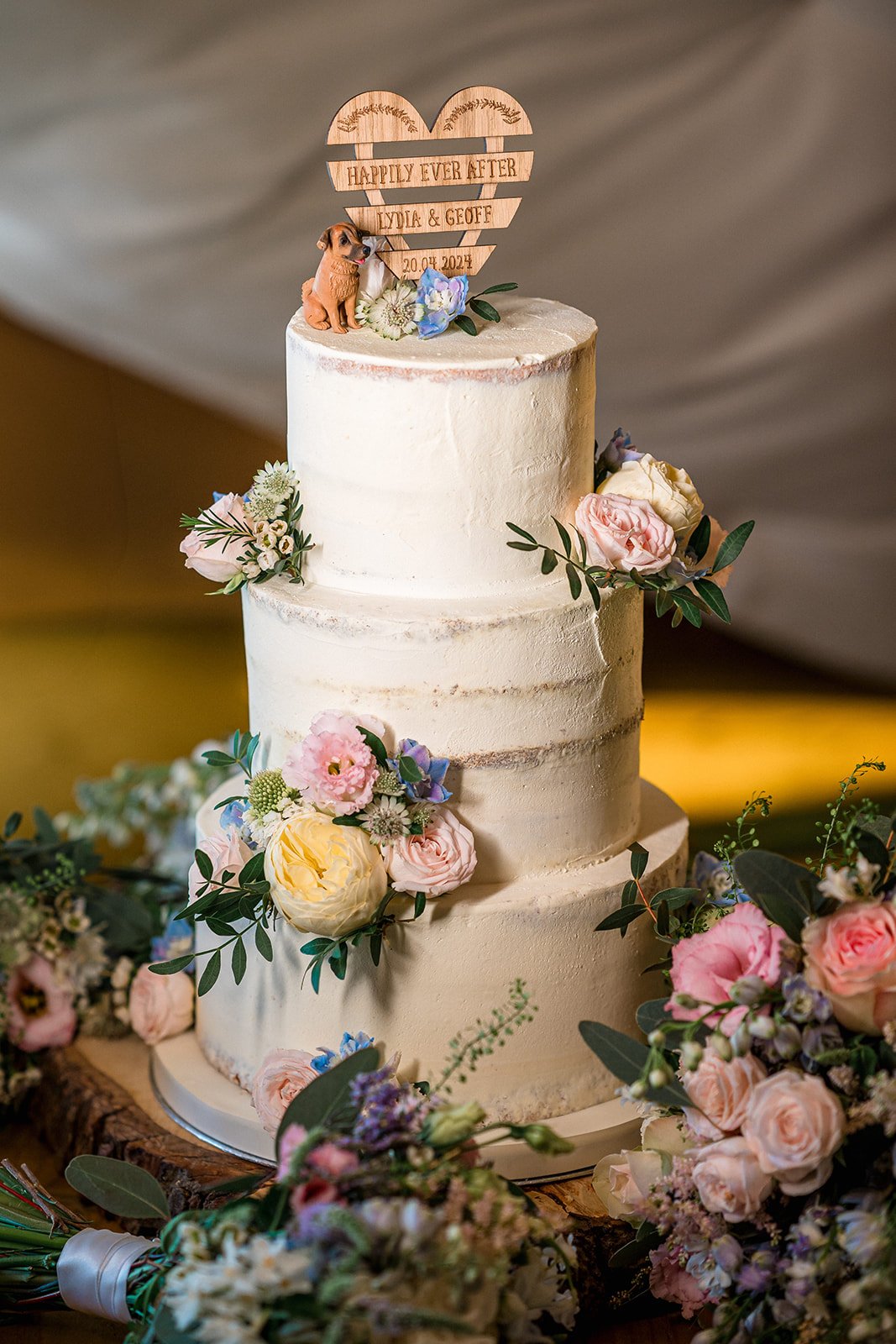 Buttercream wedding cake with clusters of fresh flowers including garden roses, waxflower and scabious
