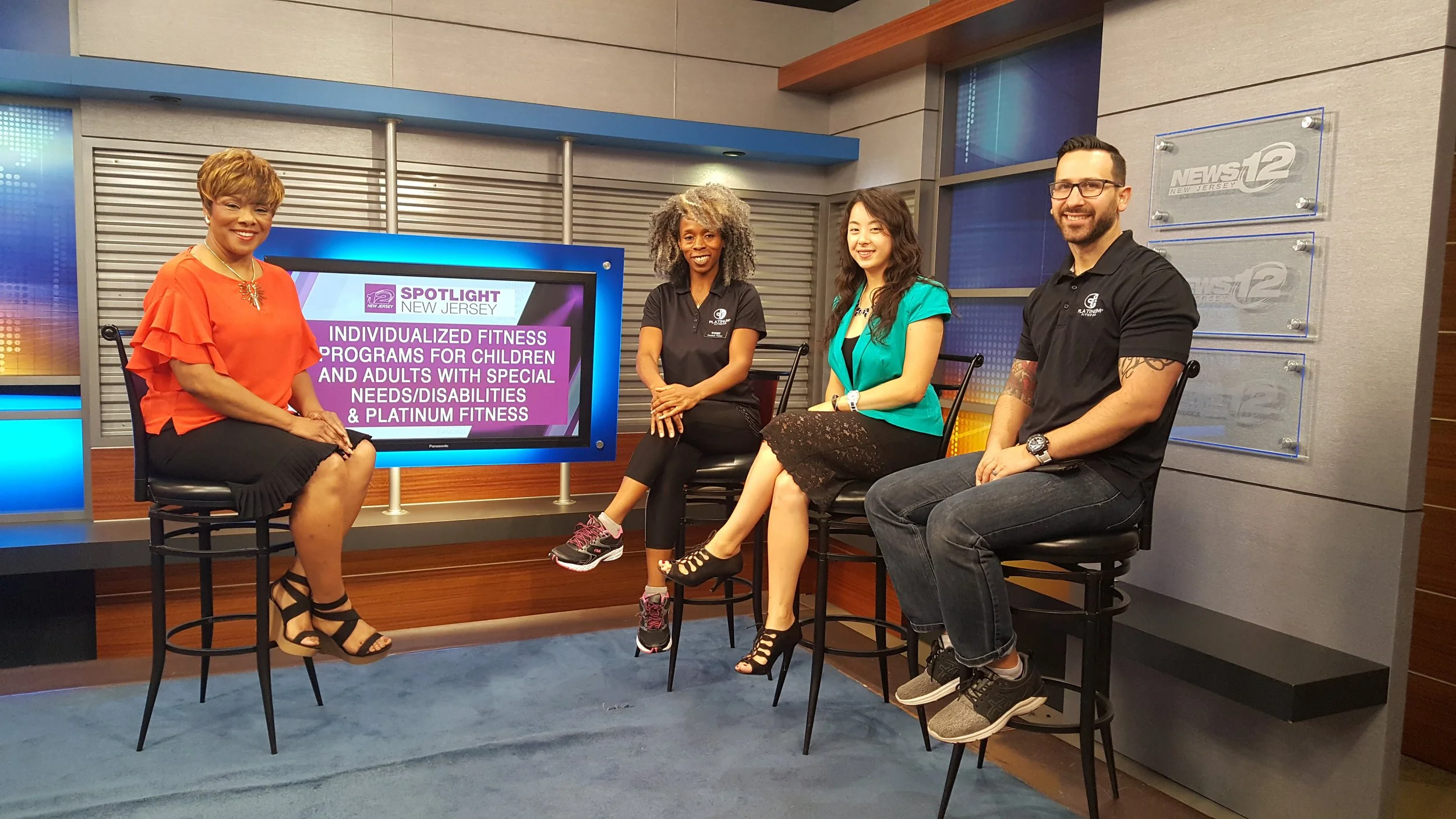 Four people sitting on stools in the television studio of News12, with a large screen behind them displaying a news segment about fitness programs for children and adults with special needs and disabilities.