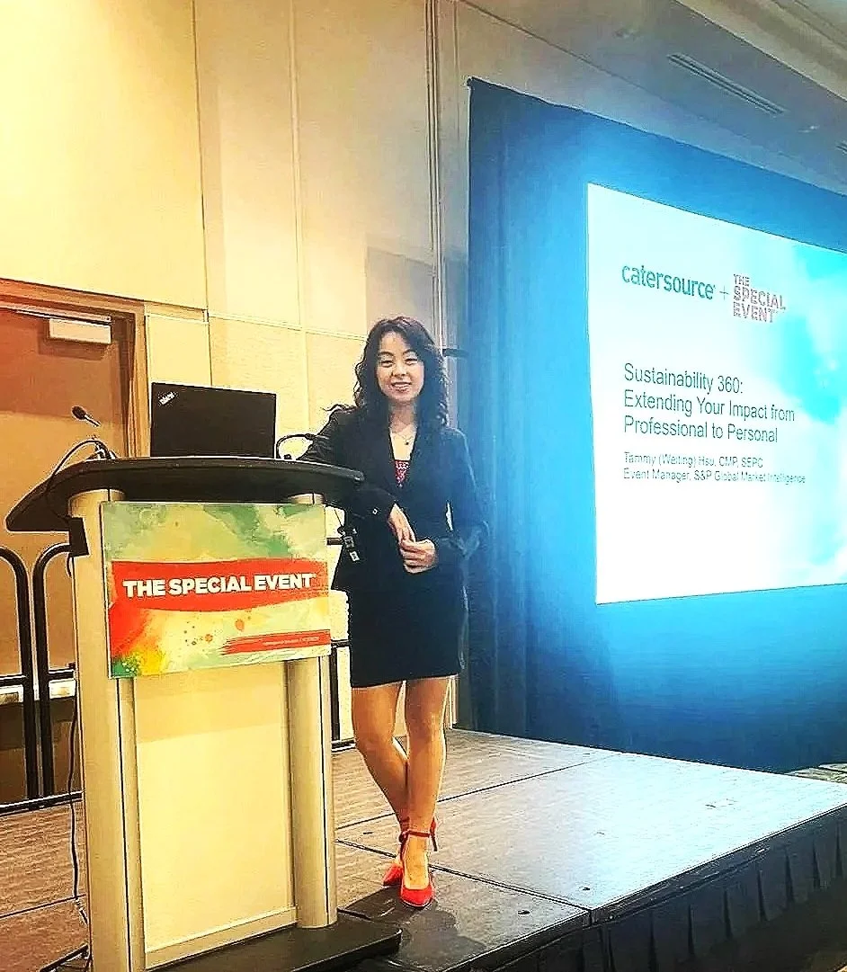 A woman standing on a stage at a conference, smiling, with a presentation screen behind her. The screen displays a presentation titled 'Sustainability 360: Extending Your Impact from Professional to Personal.' There is a podium with a sign reading 'The Special Event.'