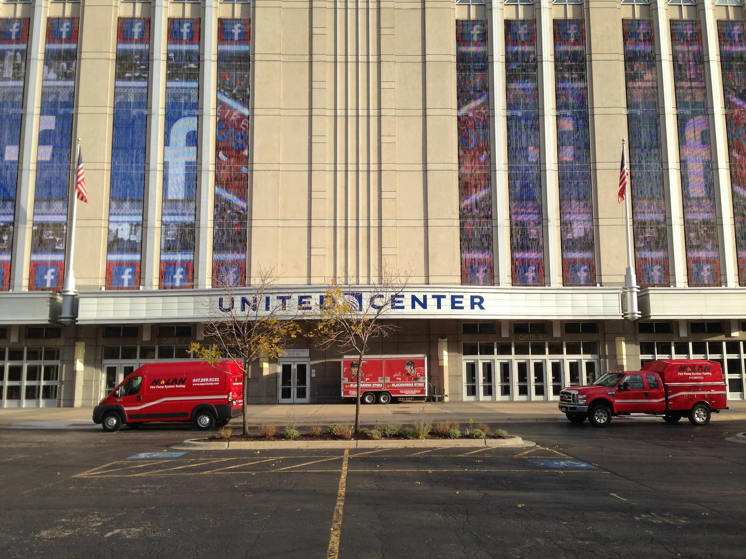 Red Van and Red Truck labeled "Nolan Fire Pump Systems" Testing parked in front of the United Center Building in Chicago