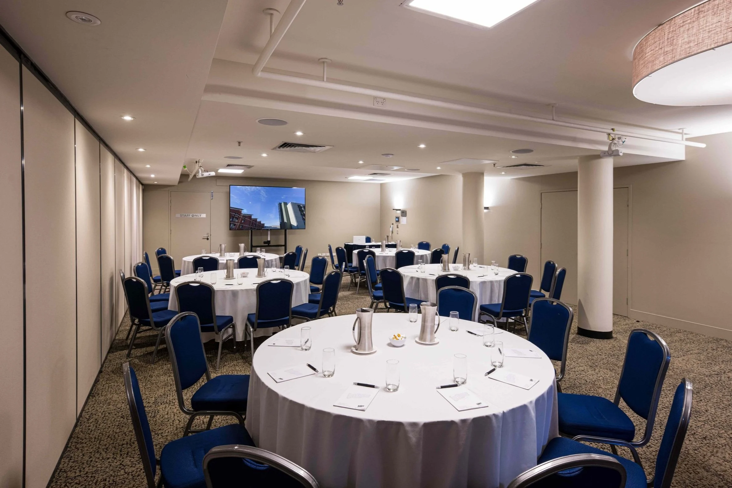 Large event room with round tables and screen