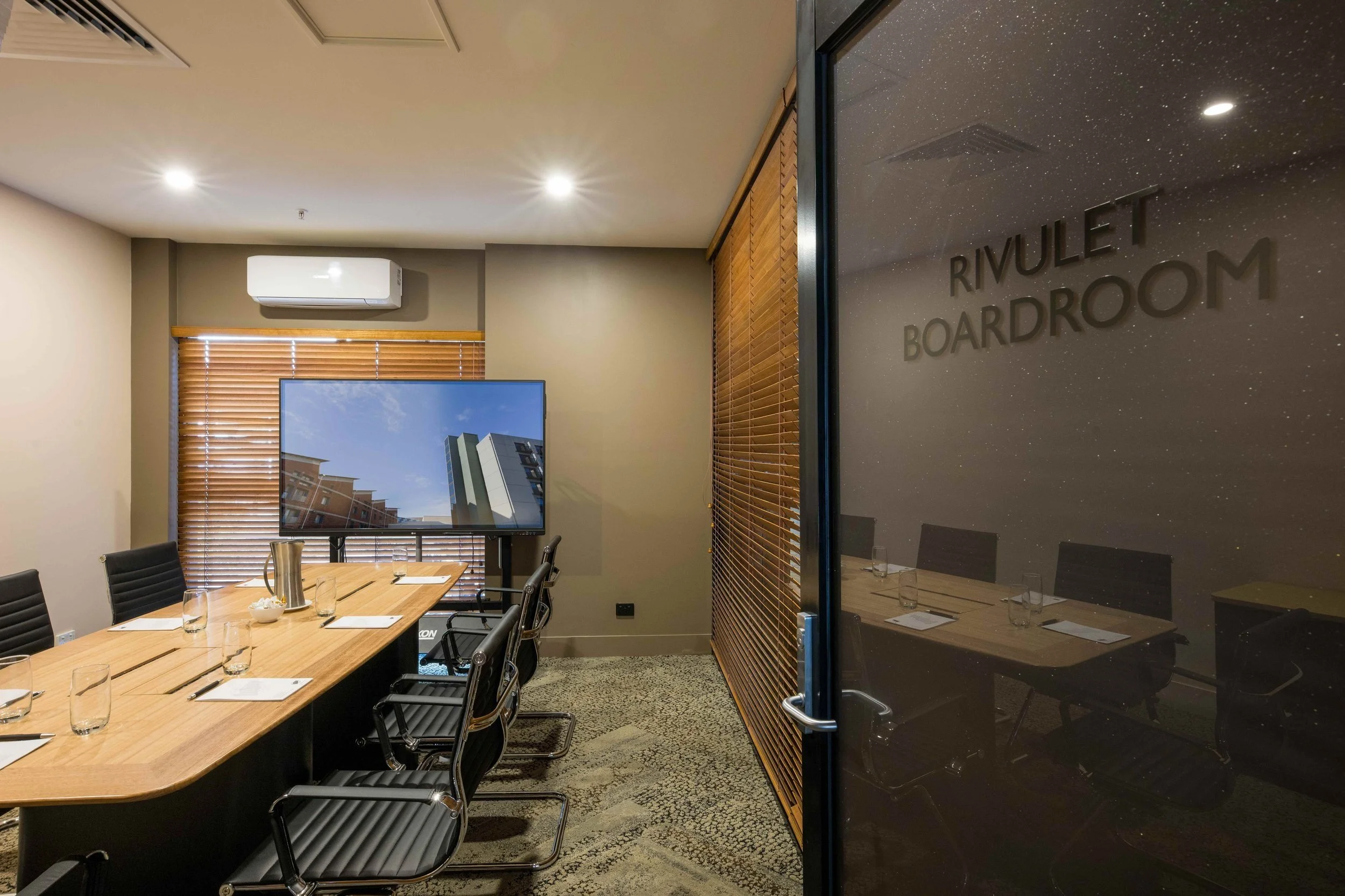 Rivulet Boardroom with large timber table and screen set for an event