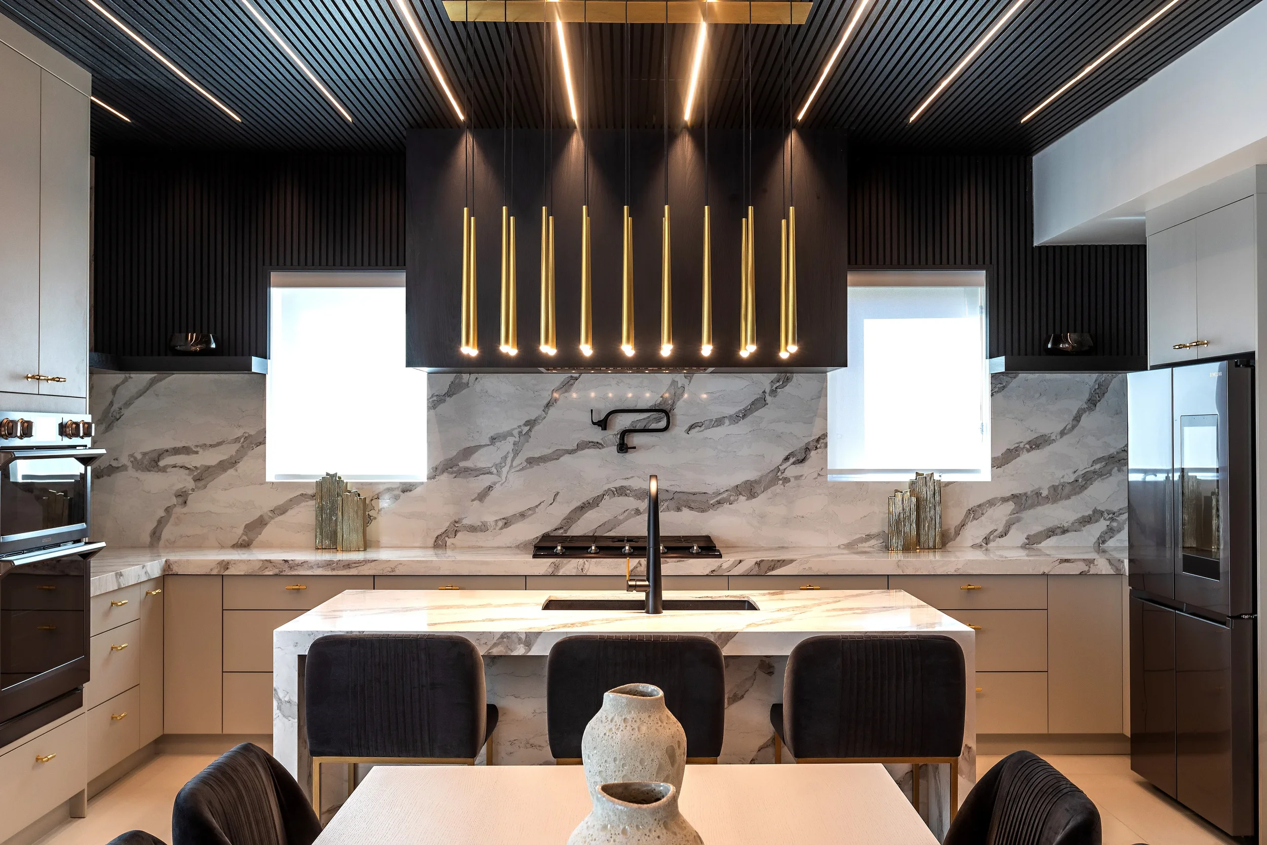 photo of a kitchen with white marble walls and countertops and black ceilings and cabinets with integrated lighting