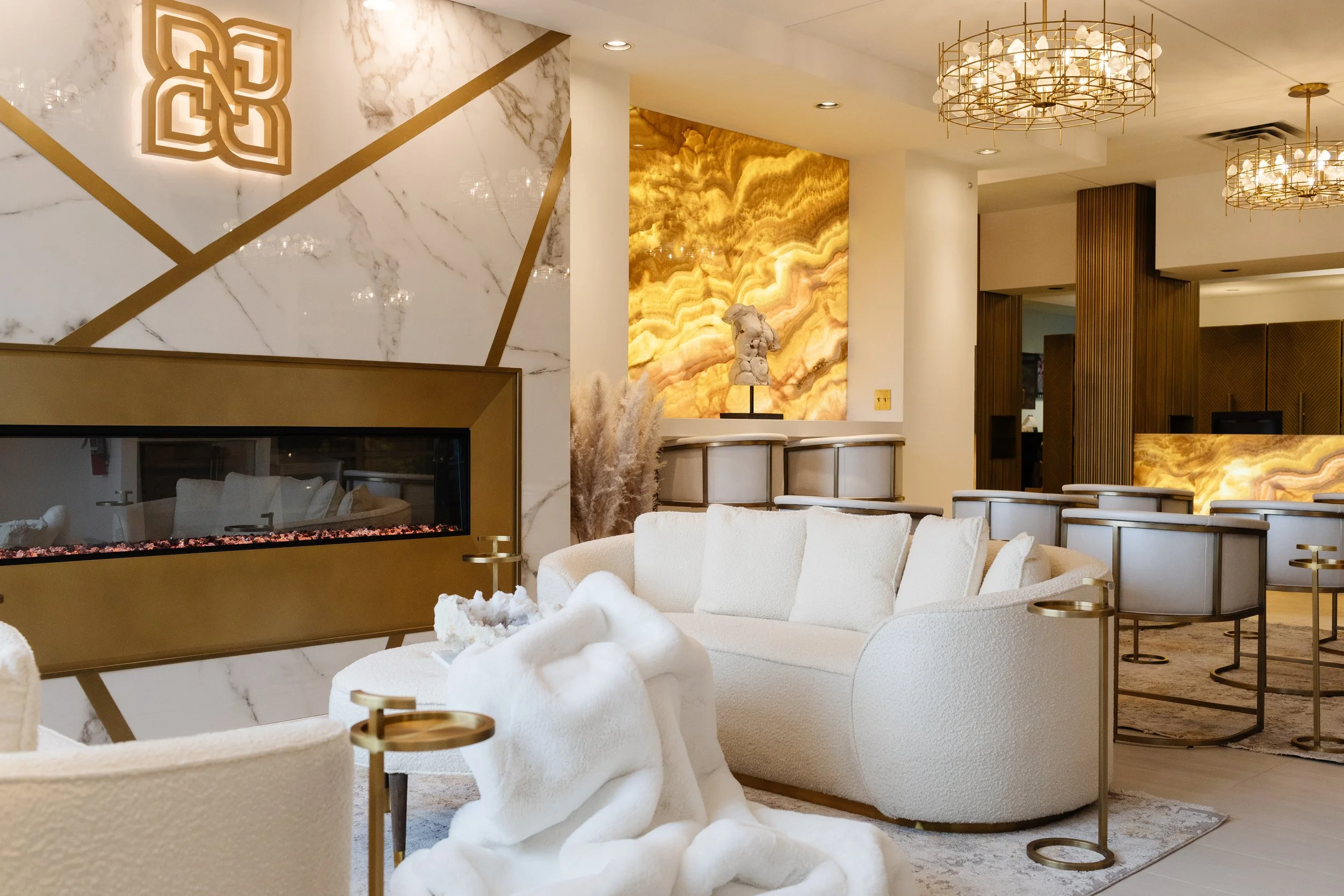 Photo of a luxury clinic waiting room with white and gold marble walls, chairs, and sofas