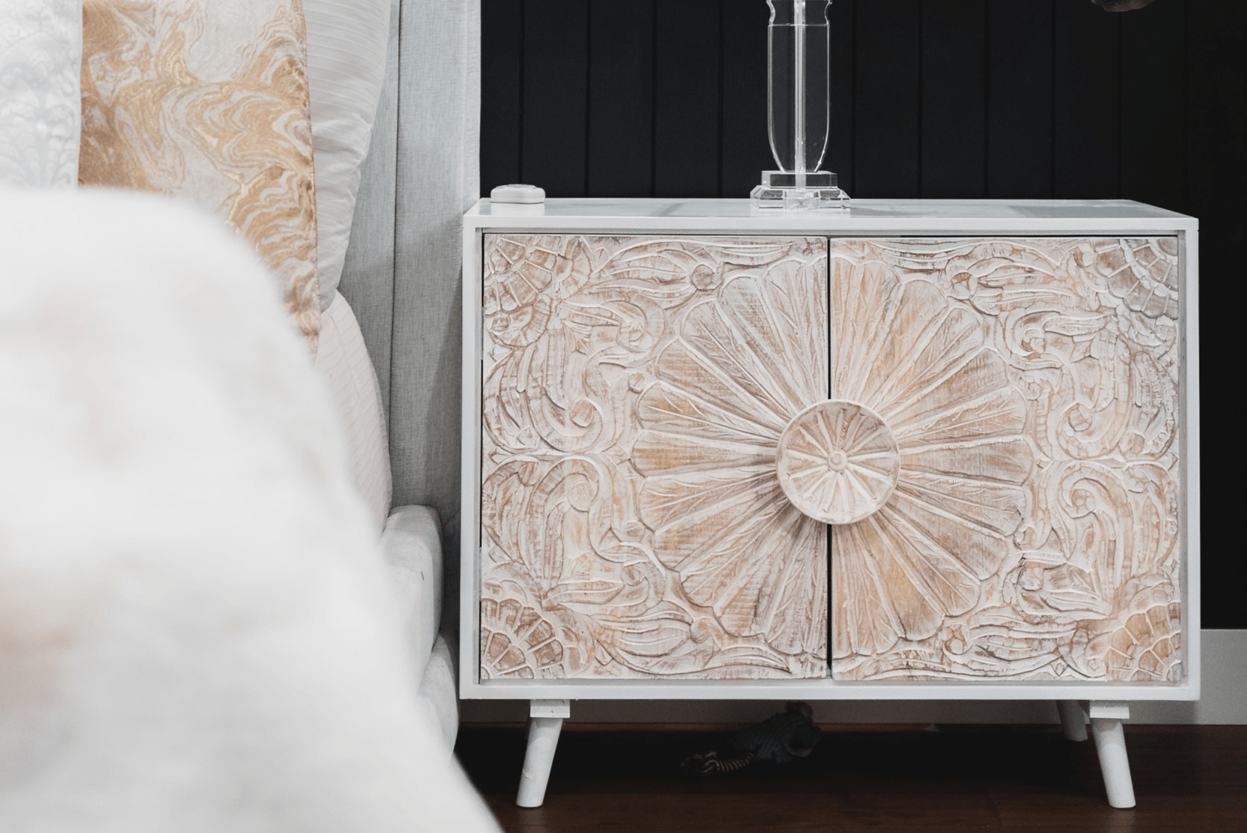 Photo of a seashell pink and white nightstand next to a white bed