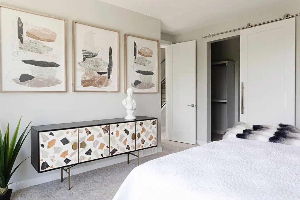 A photo of a bright modern bedroom with abstract artwork and a terrazzo-style console styled to inspire wallpaper bedroom design ideas