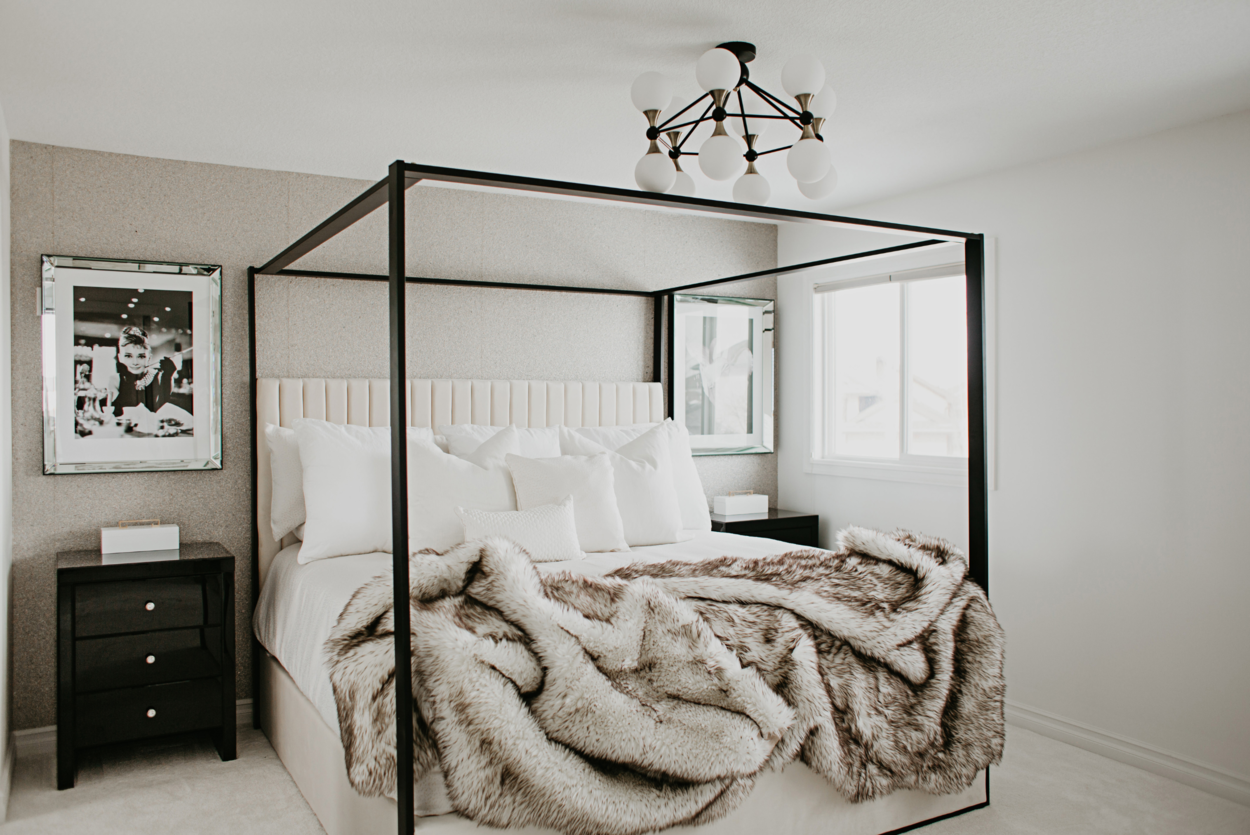 Photo of a black metal framed bed with upholstery back and fur blanket on top