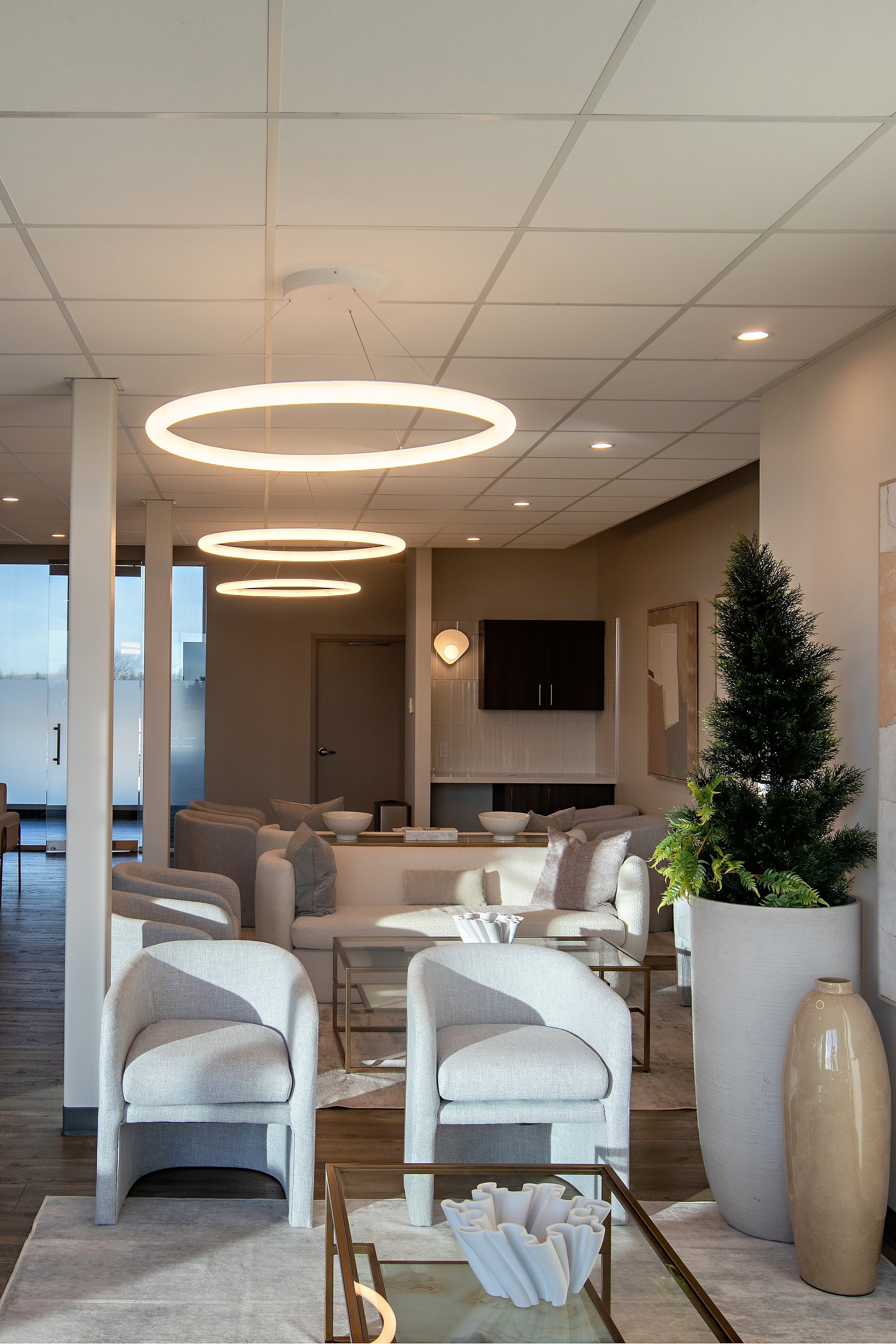 Photo of a modern waiting room commercial contractors Edmonton project with circular light fixtures above grey armchairs, decor, and a glass coffee table