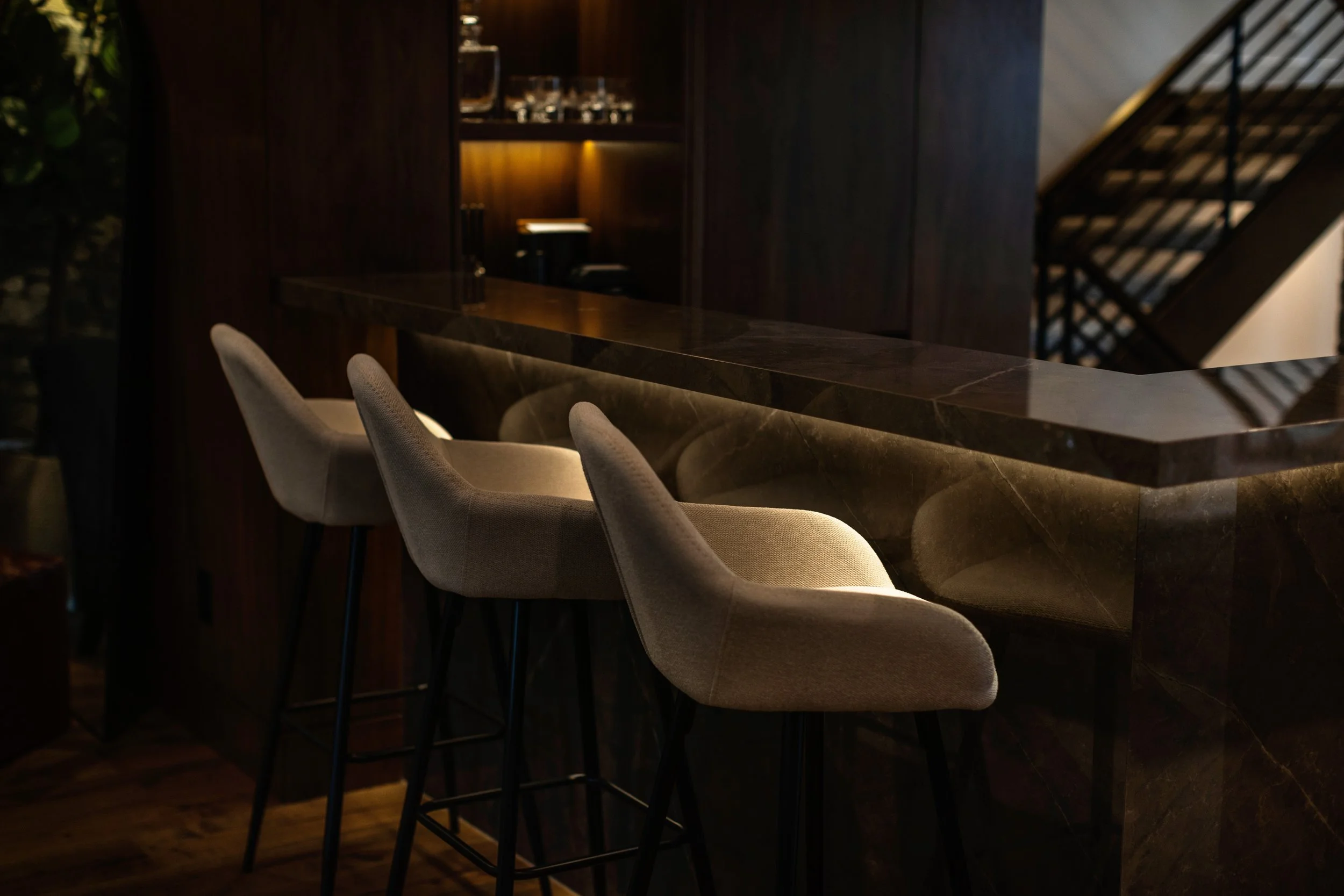 Photo-of-a-black bar table with barstools next to illuminated wall shelf