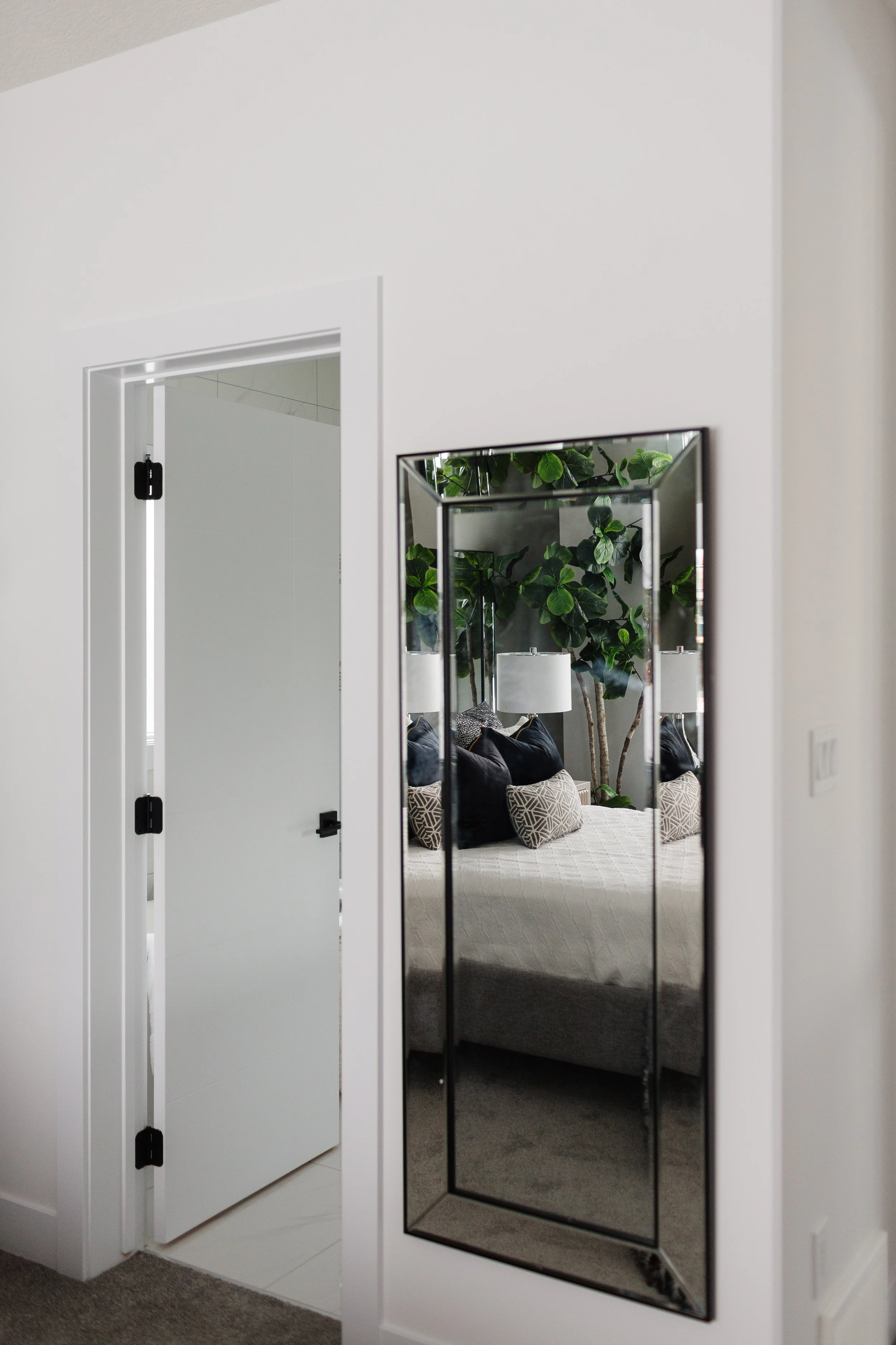 Photo of a white door open next to a mirror hanged on the wall
