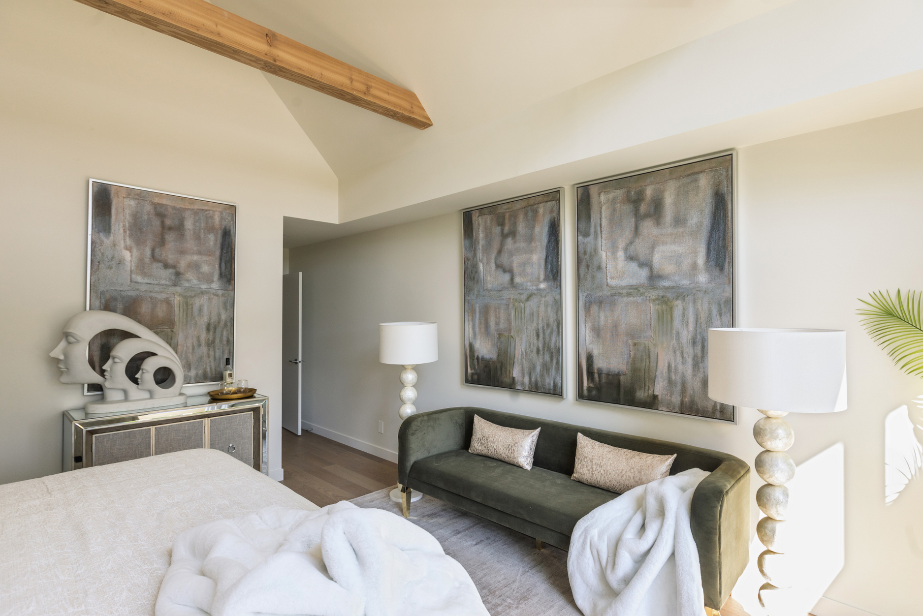 Picture of styled bedroom interior featuring a green sofa, artwork, lamps, and a face figure styled in a green, beige, off-white, and white colour palette