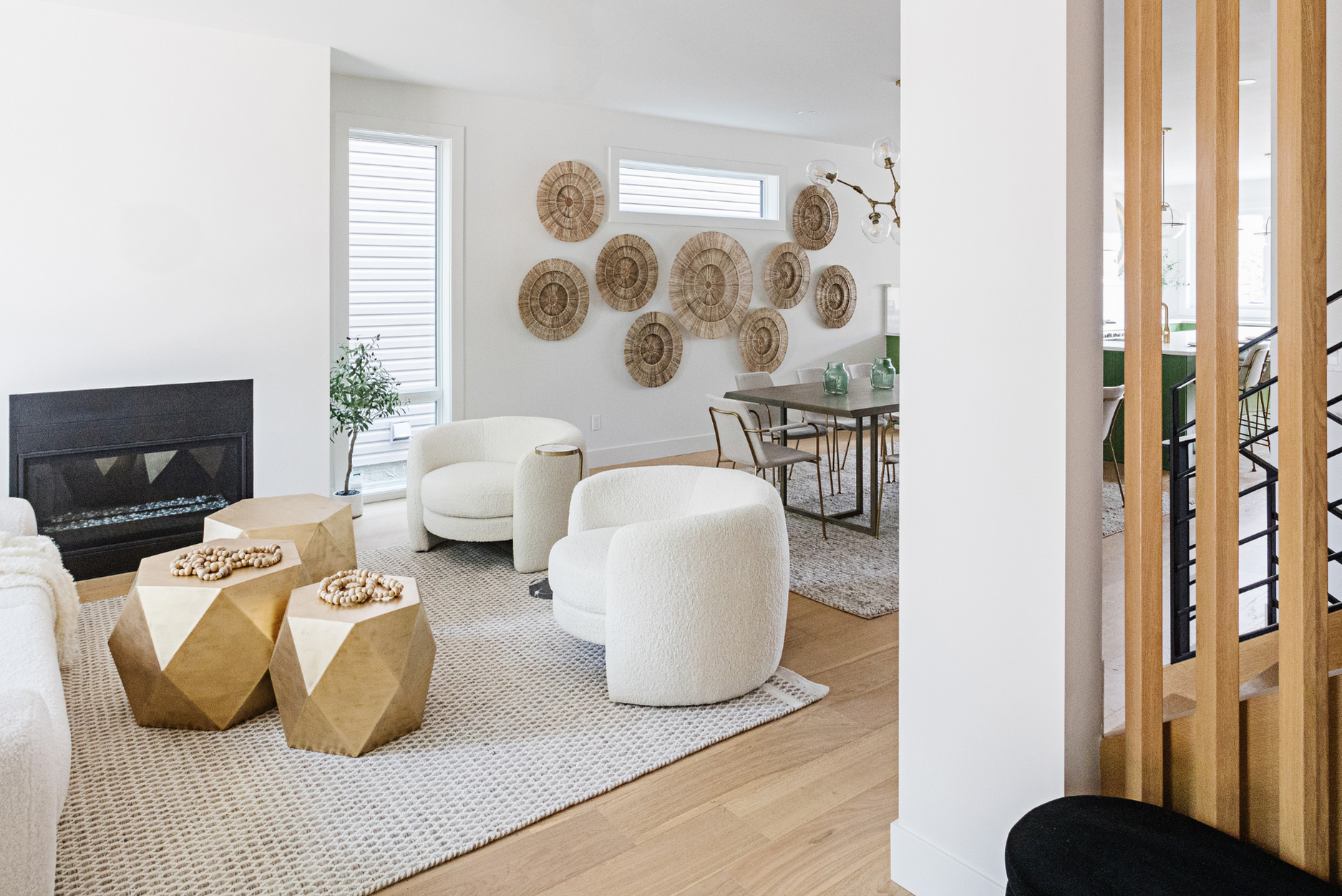 Photo of a living room with white armchairs seated around gold coffee tables and a fireplace on top of a patterned rug showing how to use rugs in interior design