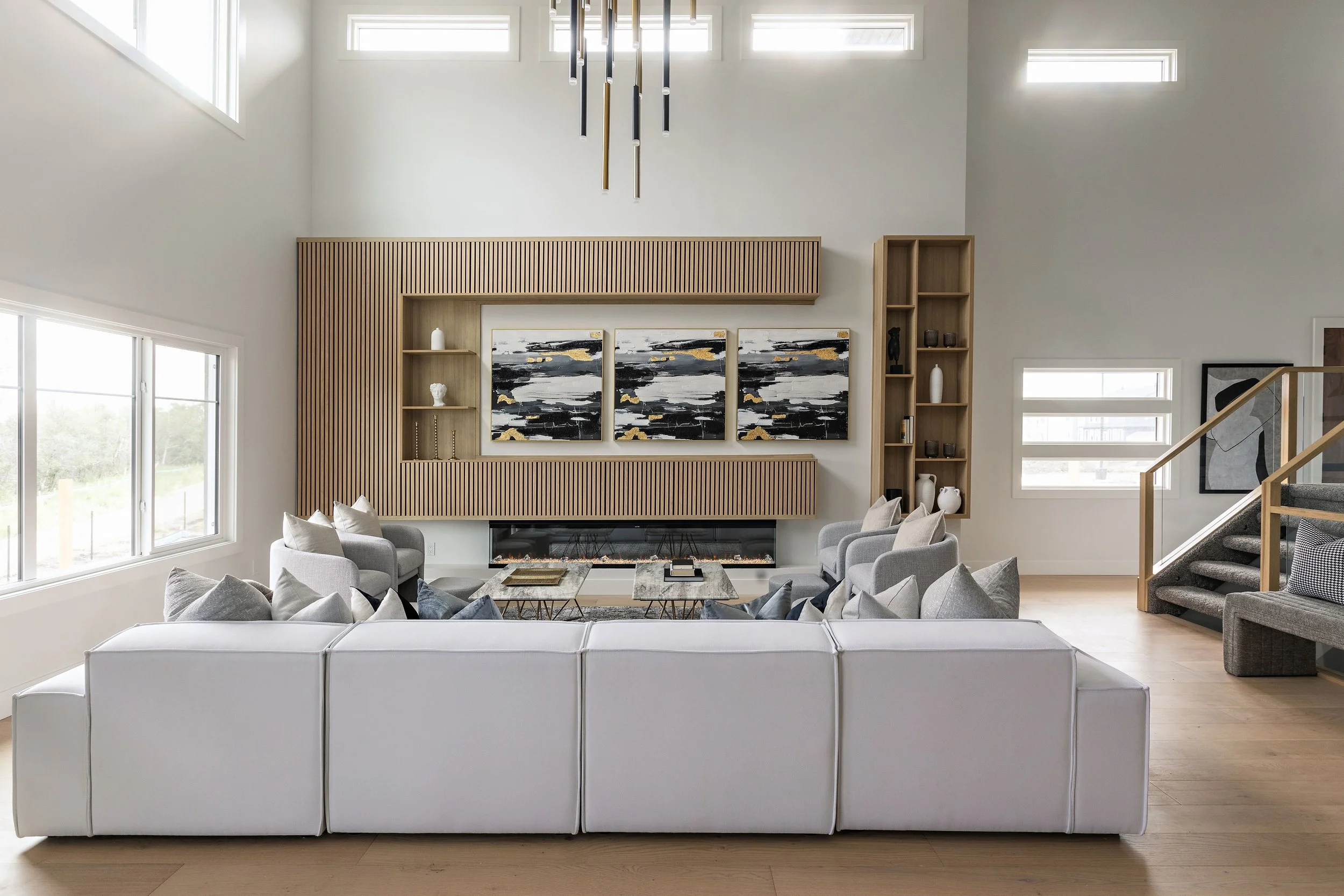 Photo of a modern white living room with a white sofa facing a gold entertainment console with three pieces of matching artwork on the wall