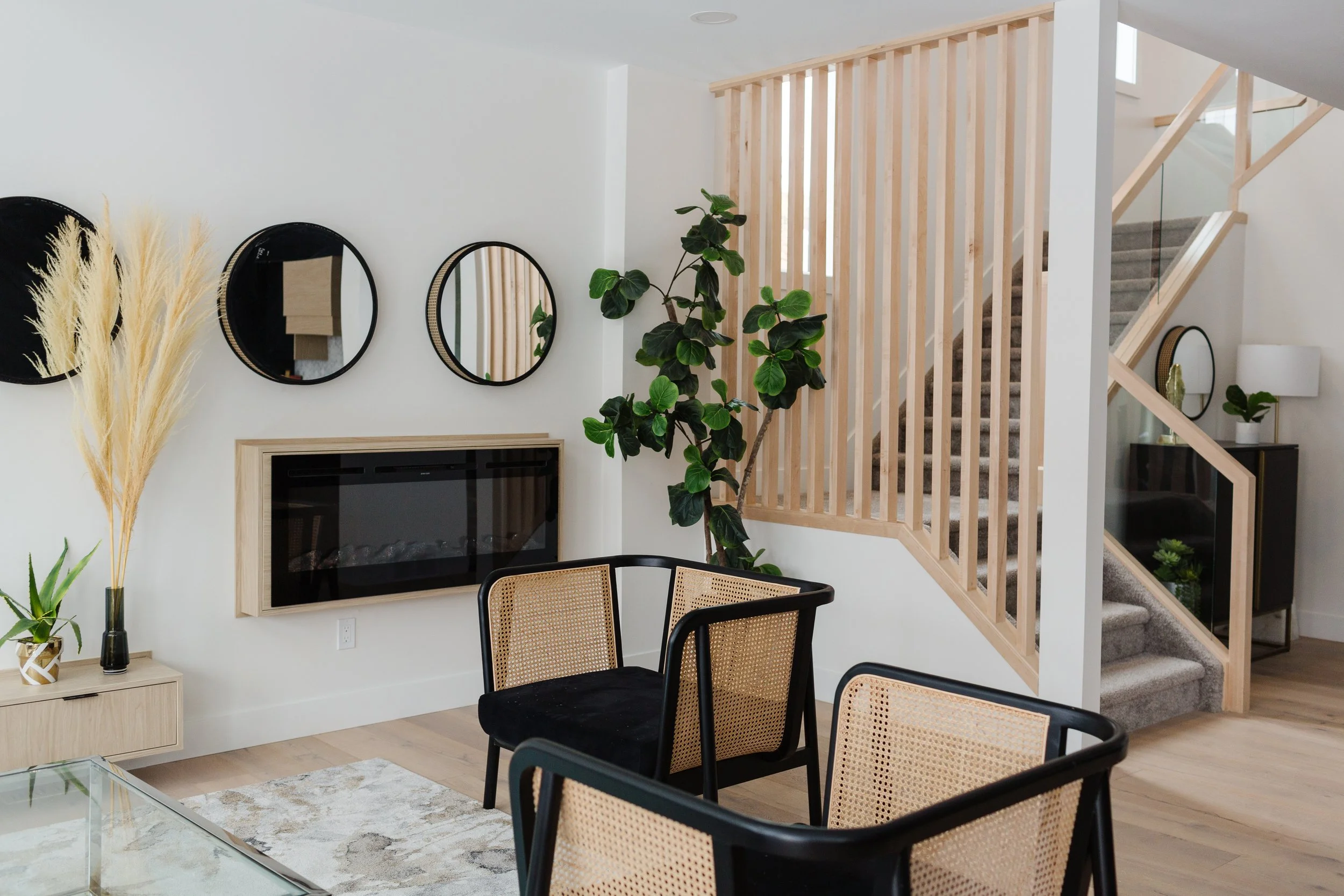 Photo of a white minimalist living room with black bamboo furniture next to a wall with mirrors and a built-in fireplace next to a wood side table