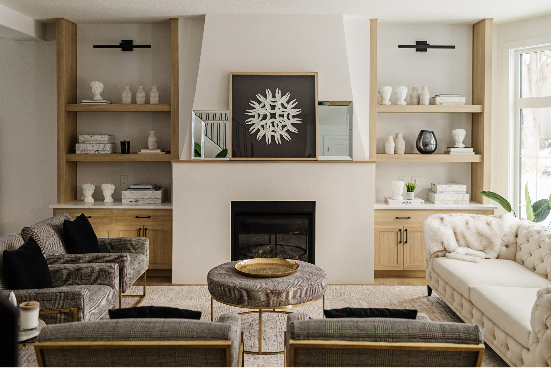 Photo of a white modern living room with plaid chairs facing a fireplace surrounded by book shelves with decor