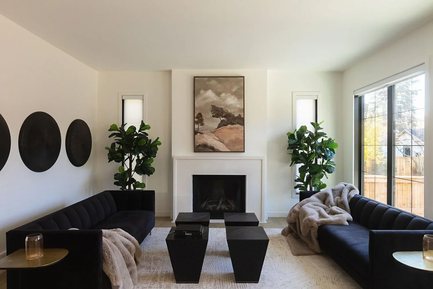 photo of two black sofas facing each other around a white marble fireplace