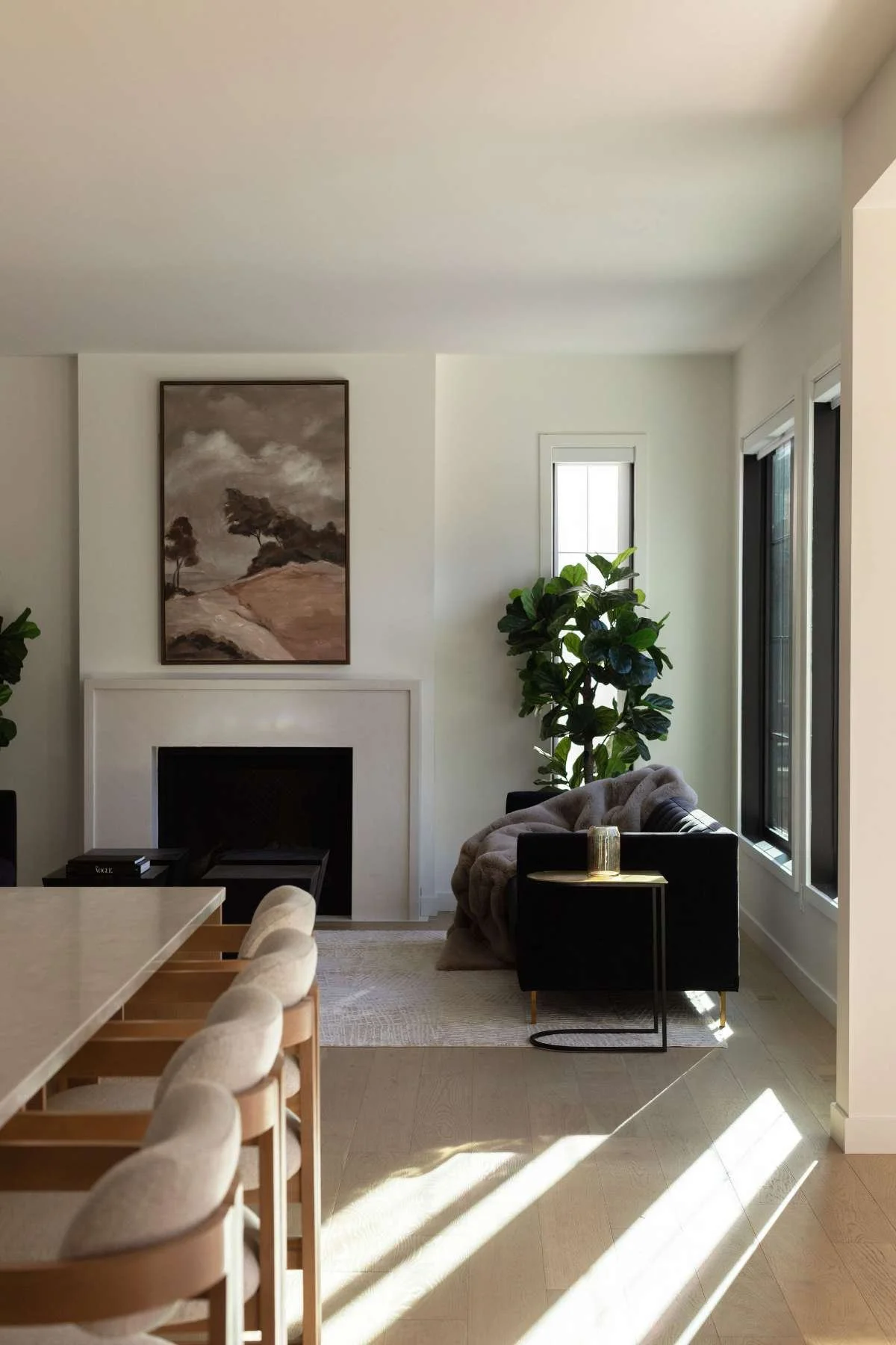 Bright, modern interior featuring a minimalist dining and kitchen space with natural light, neutral tones, wood accents, and contemporary furnishings.