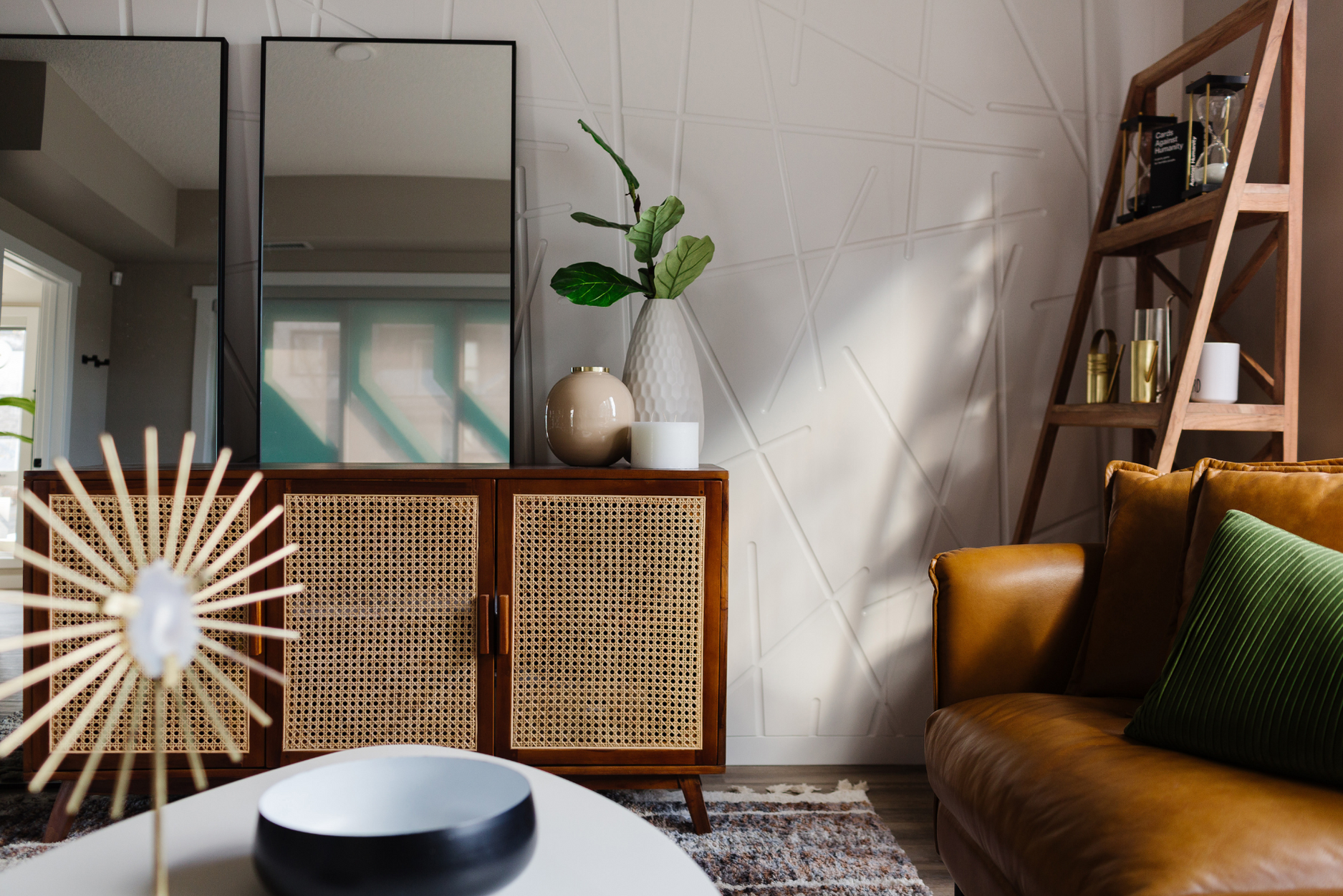 Photo of a modern japandi inspired interior space with textured light coloured walls wicker accented furniture leather sofa and decorative mirrors