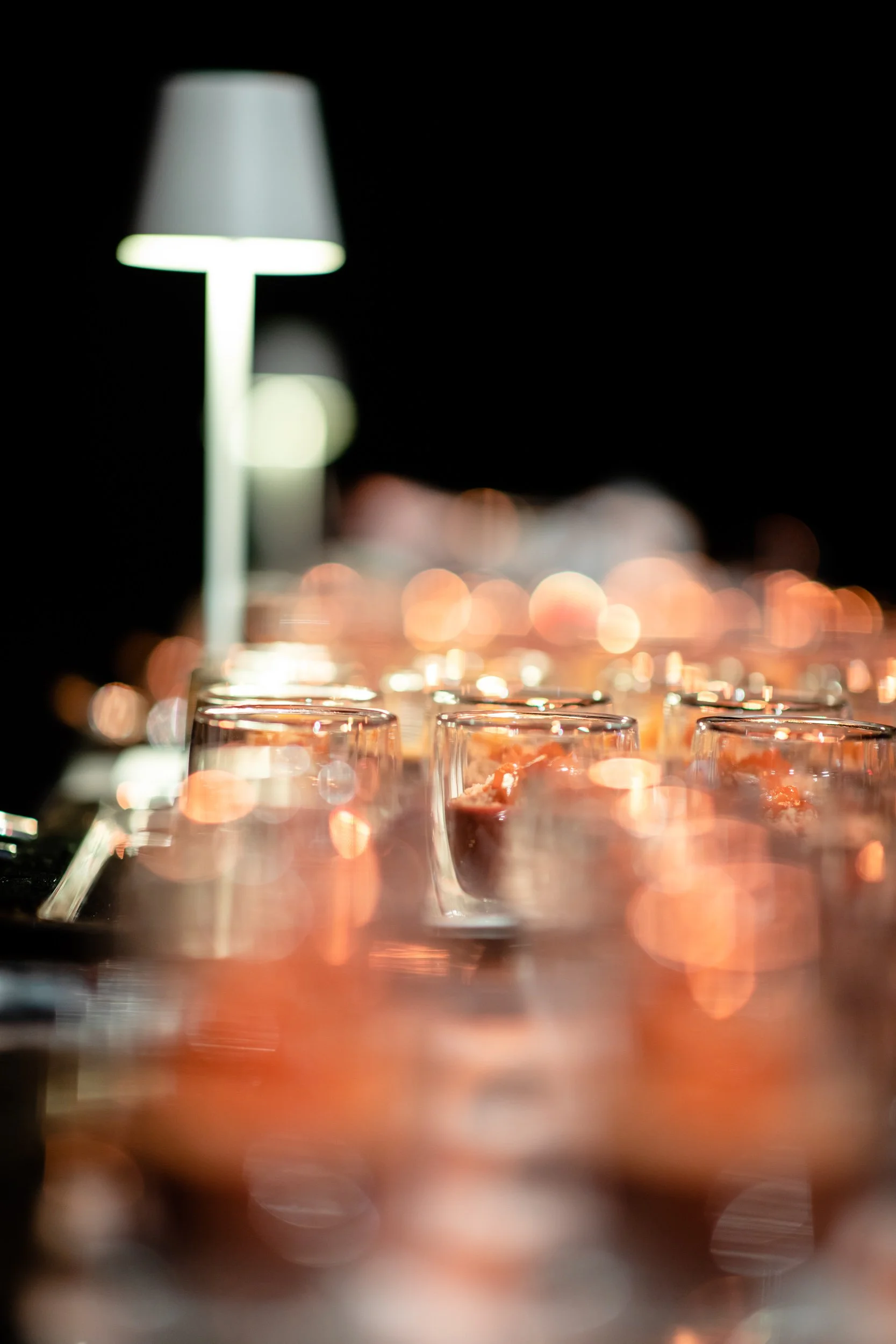 Abstract image of a table with a row of glowing candles and a blurred lamp in the background.