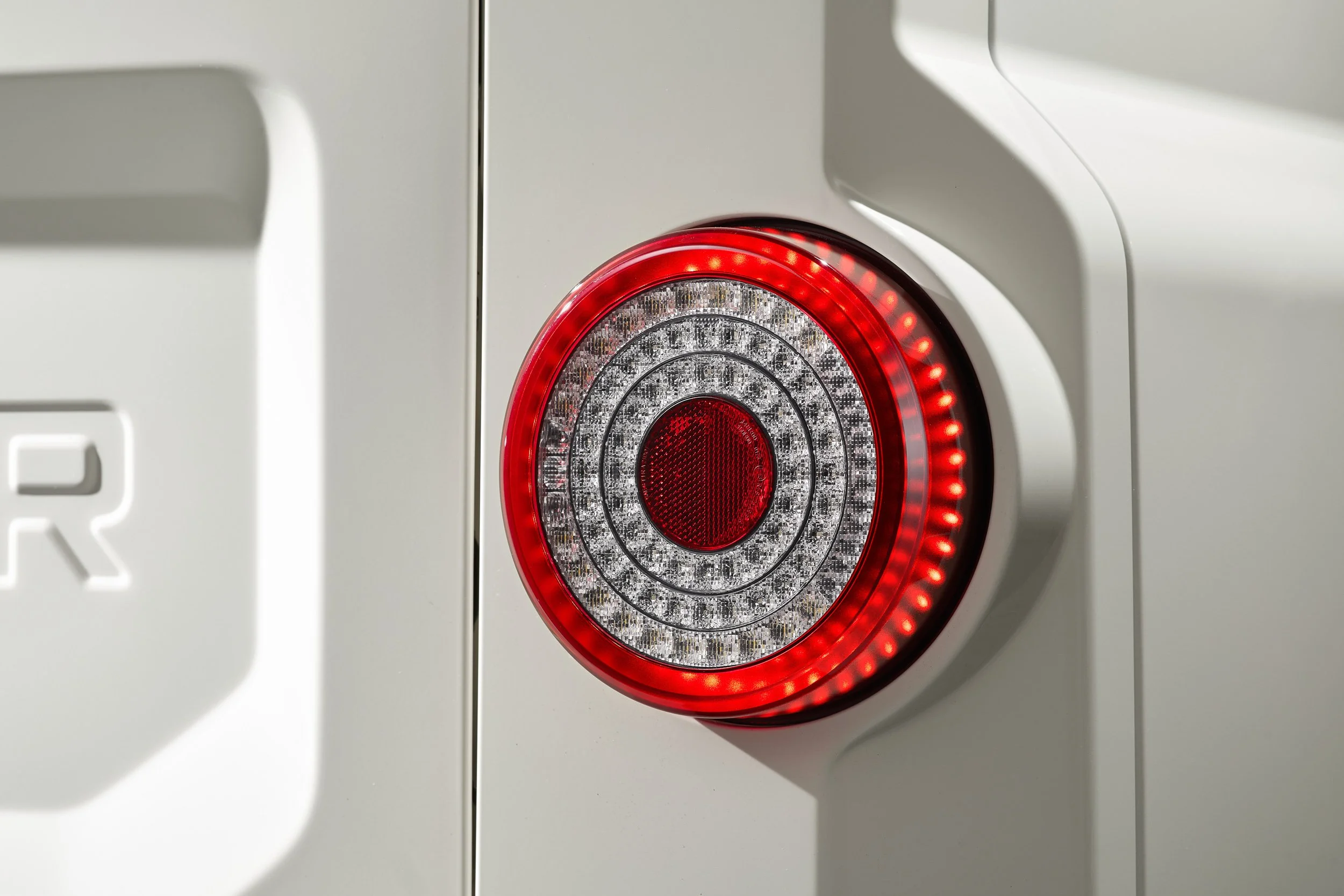 Close-up of a vehicle's circular red and white LED taillight.