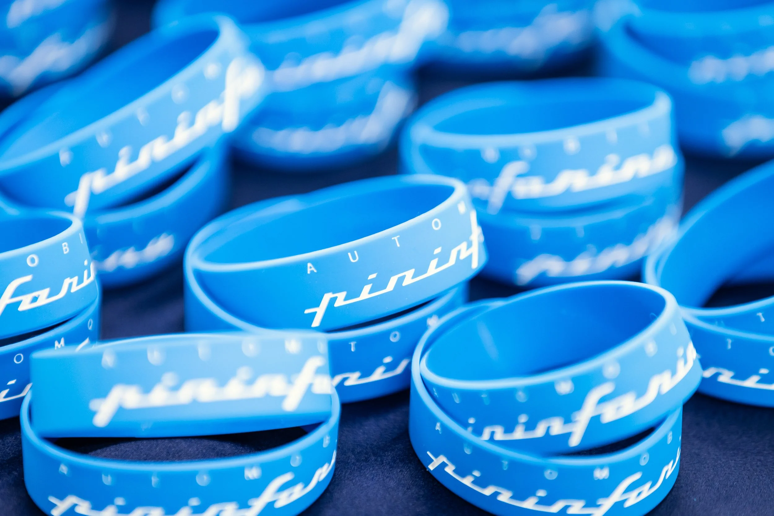 Blue silicone wristbands with white script text on a dark surface.