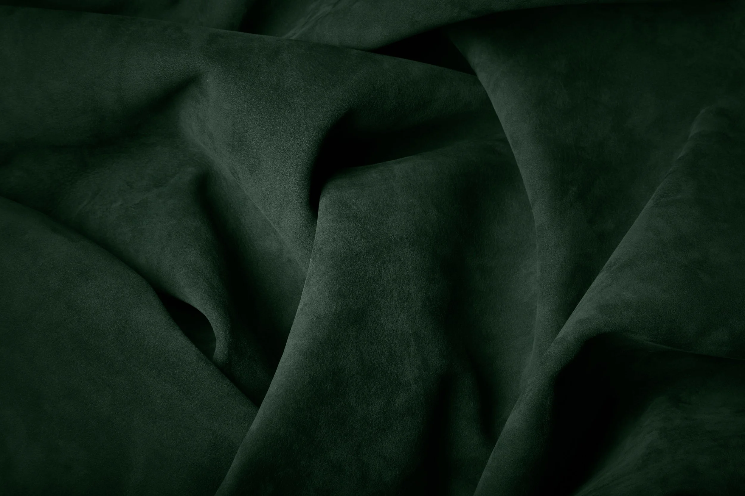 Dark green suede fabric with folds and texture.