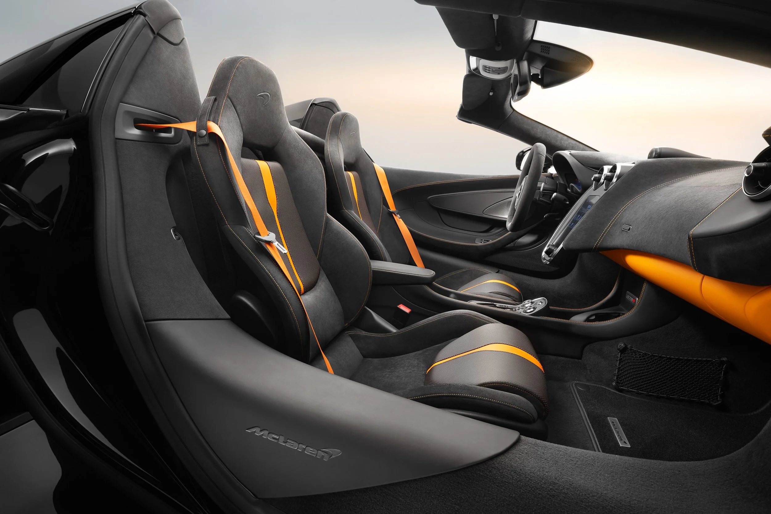 Interior of a luxurious sports car with black and orange leather seats, sophisticated dashboard, and advanced steering wheel design.