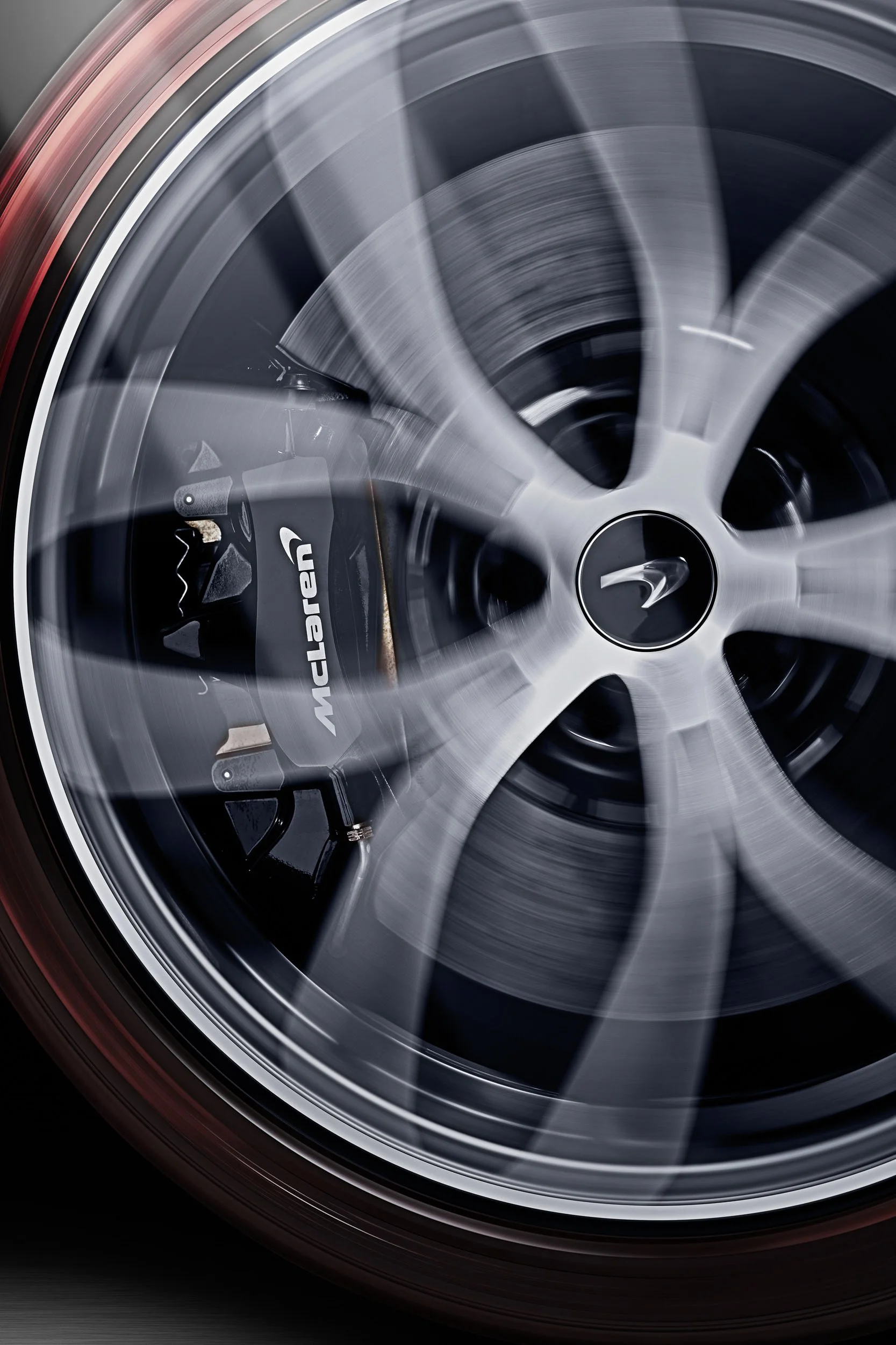 Close-up of a spinning McLaren wheel with a visible brake caliper and logo.