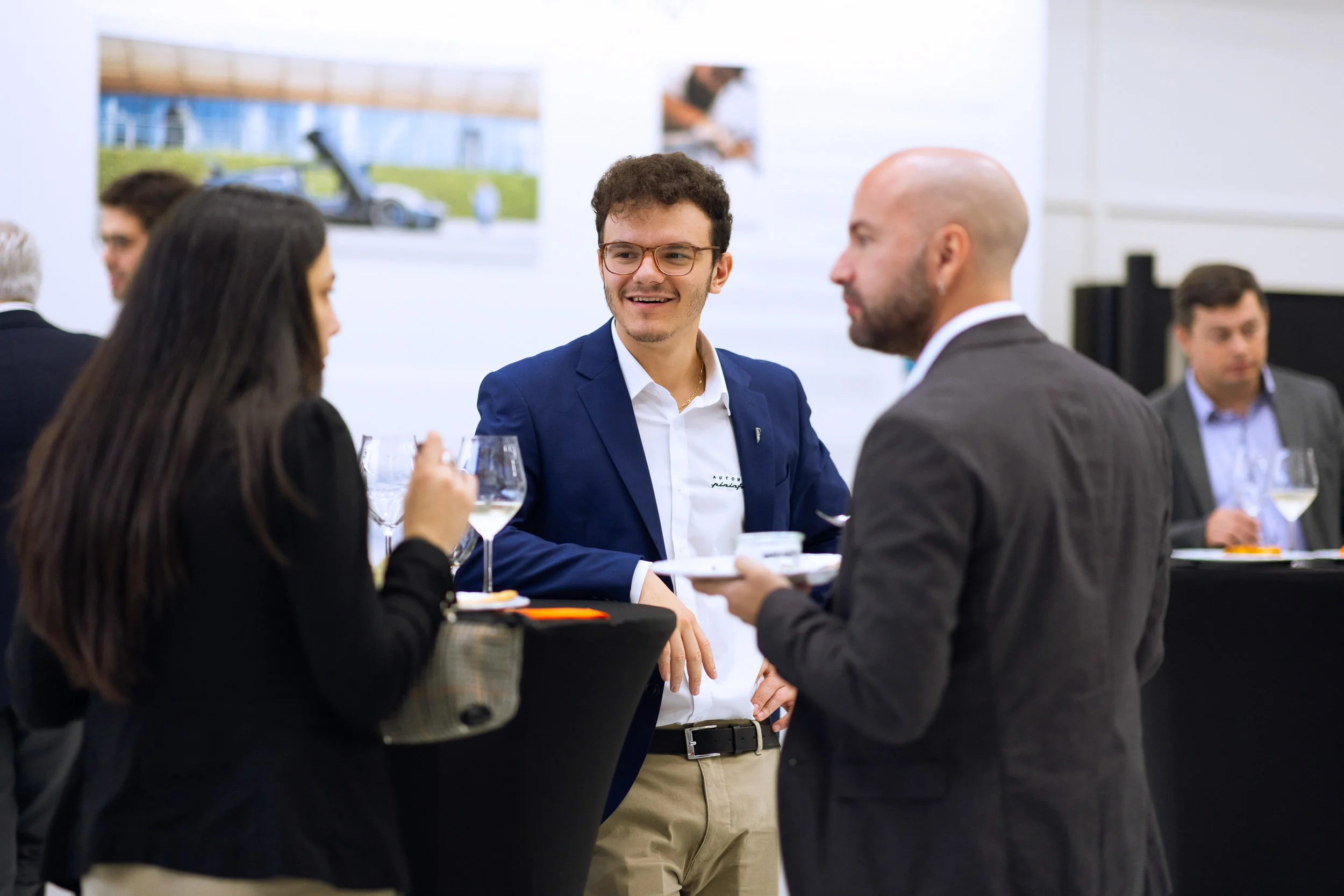 Group of people networking at an event, conversing around cocktail tables.