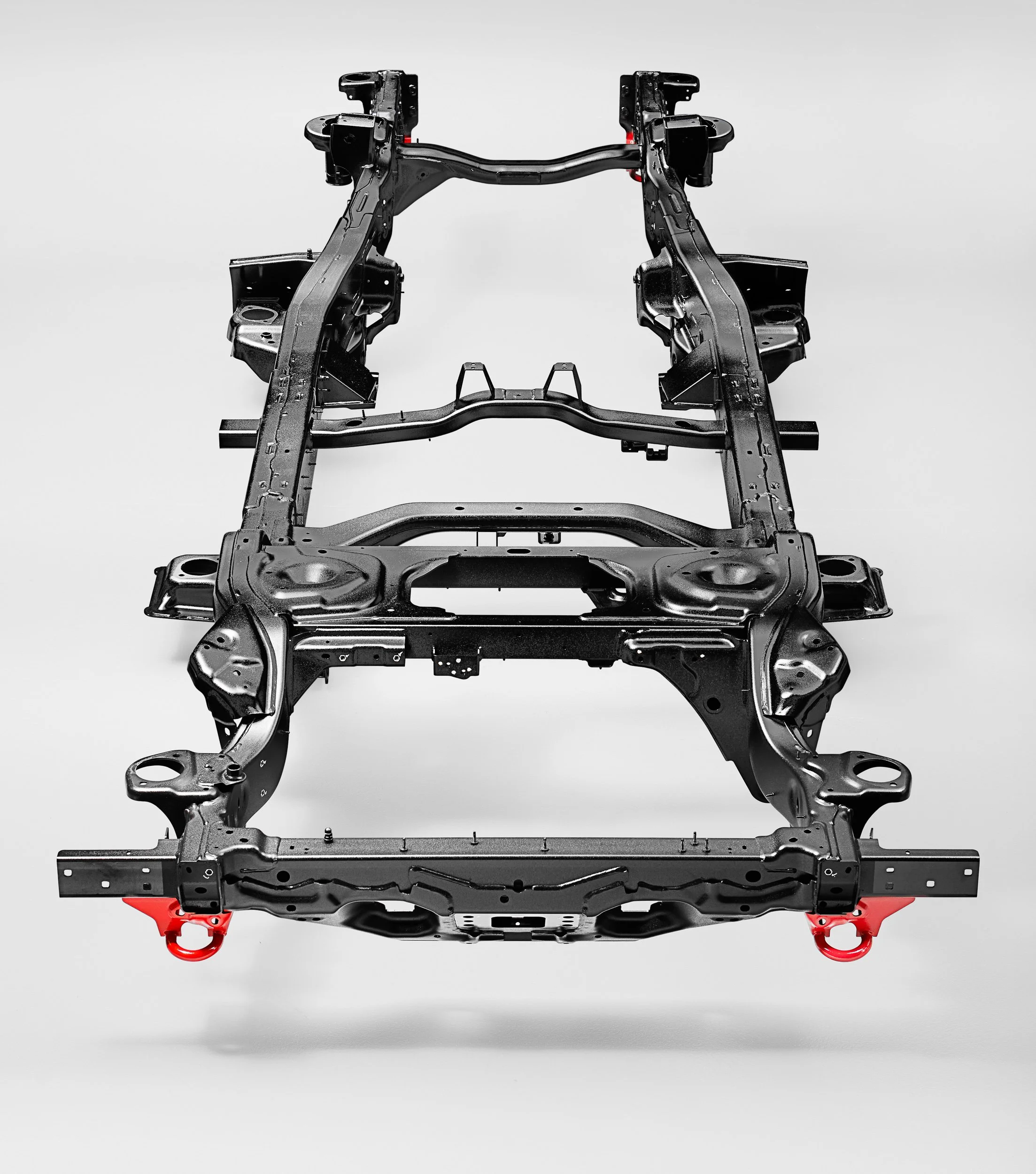 Vehicle chassis framework with red towing hooks on a grey background.