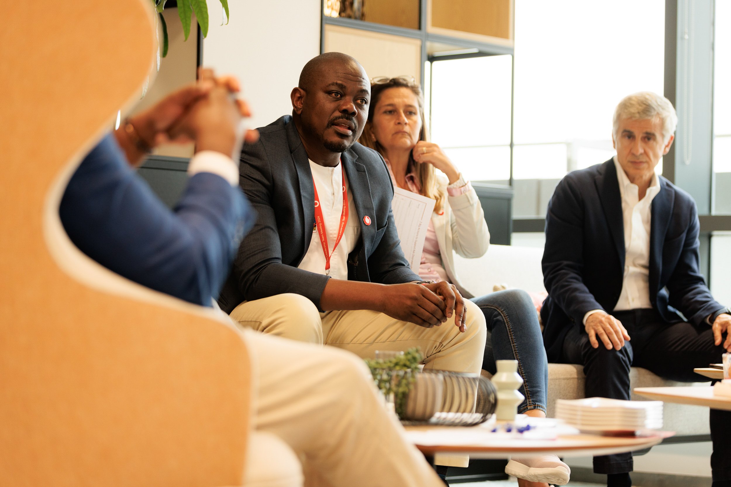 Group of people in a business meeting, sitting on a couch, engaged in discussion.