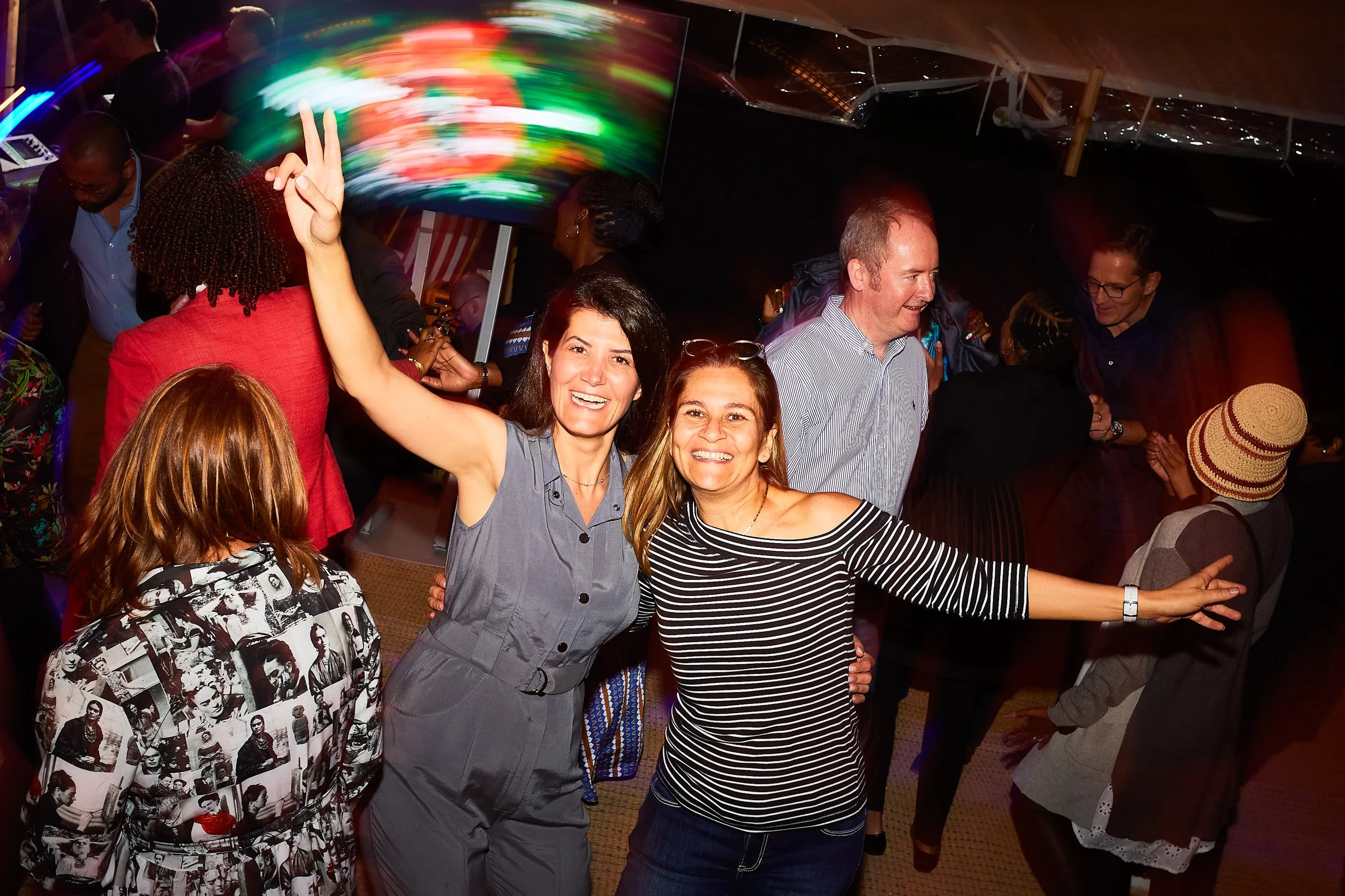 Group of people dancing and having fun at a party with colorful lights.